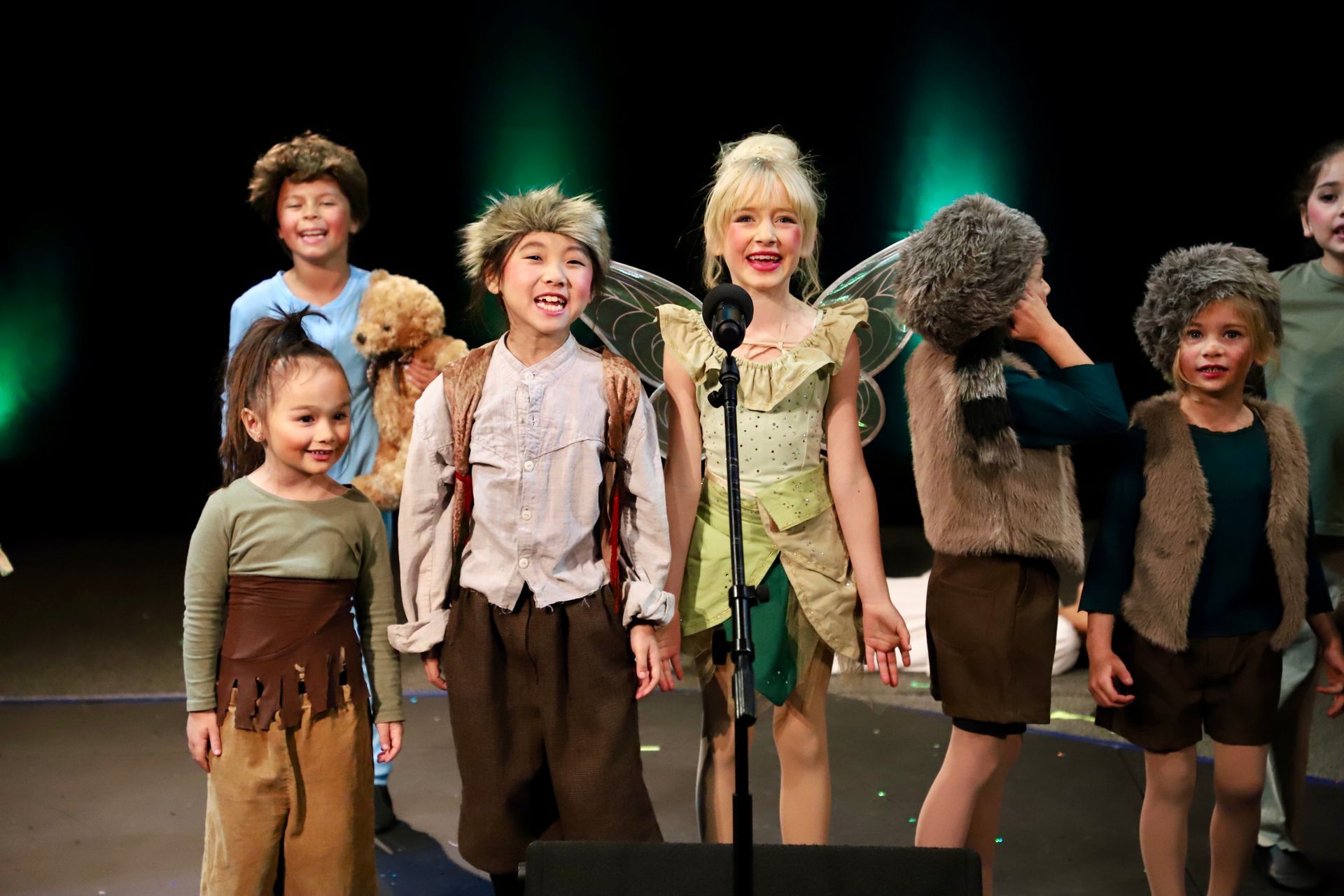 A group of children are standing in front of a microphone on a stage.