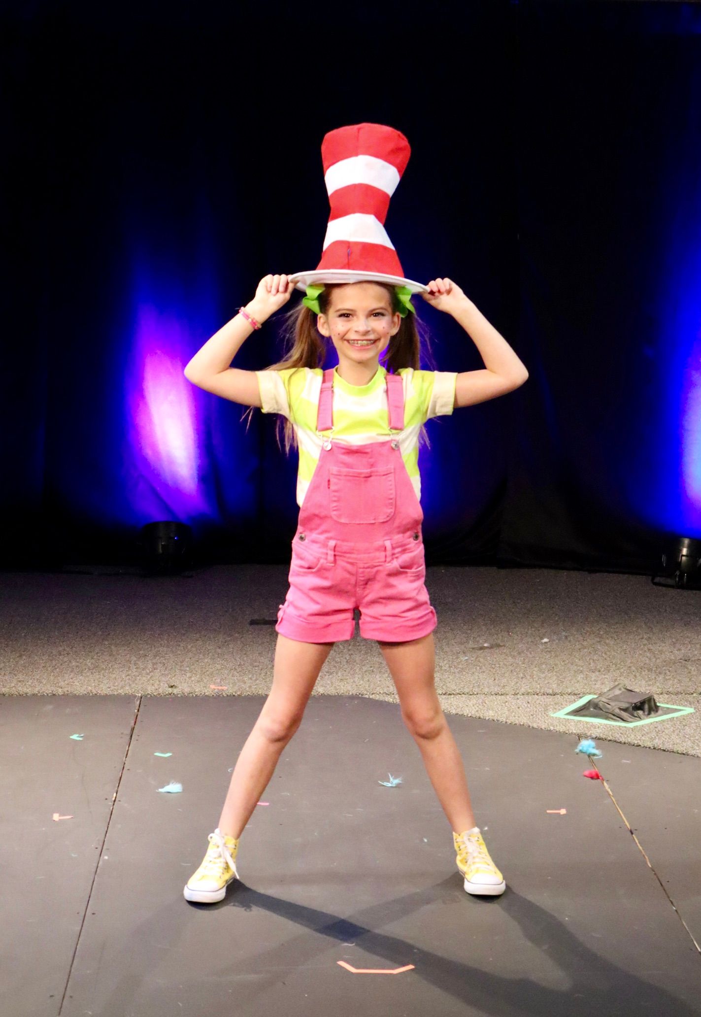 A little girl is wearing a cat in the hat costume