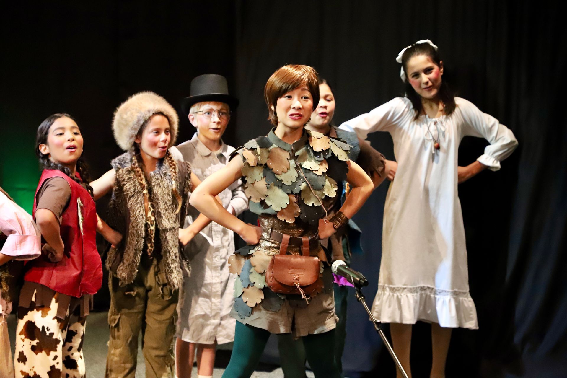 A group of people are standing on a stage with their hands on their hips.