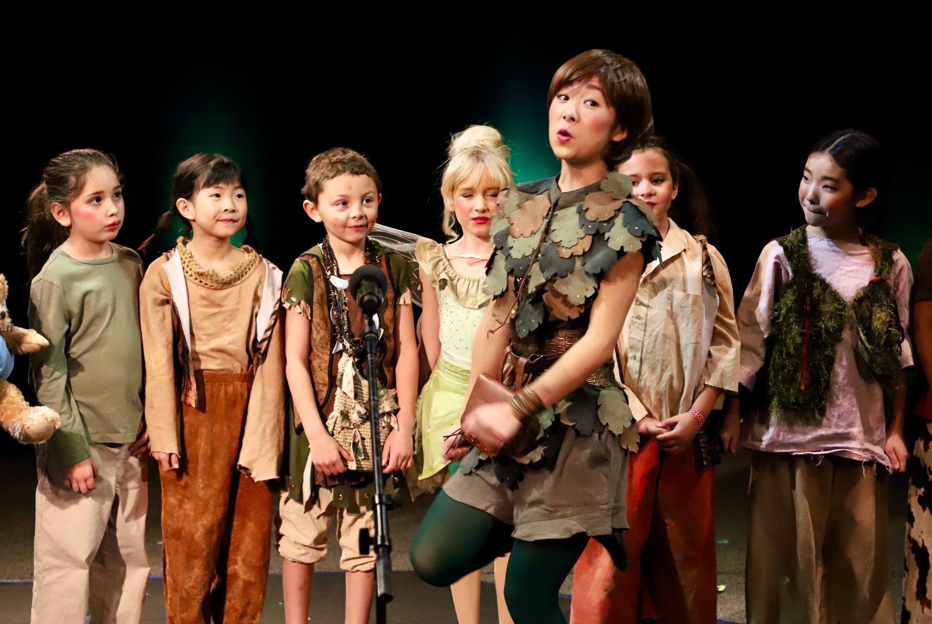 A group of children are standing in front of a microphone on a stage.