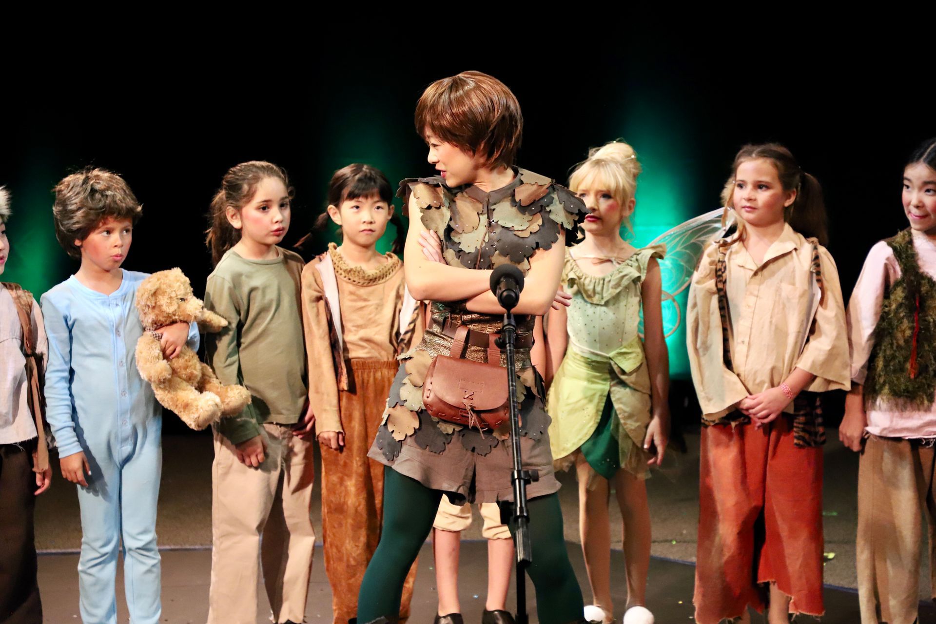 A group of children dressed as peter pan are standing on a stage.