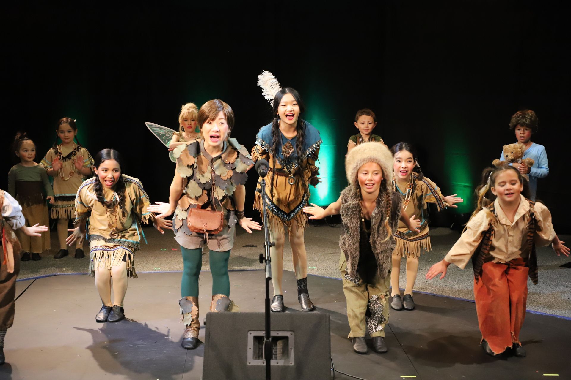 A group of children are dancing on a stage in front of a microphone.