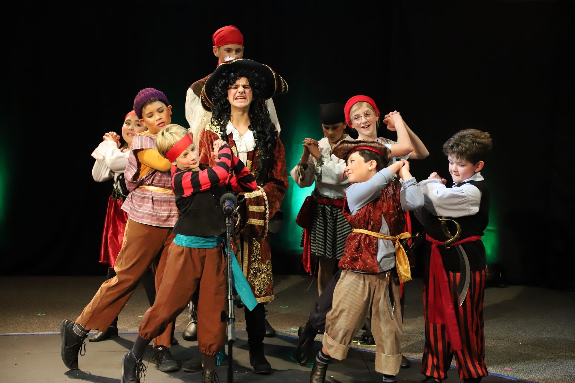 A group of children dressed in pirate costumes are standing on a stage.