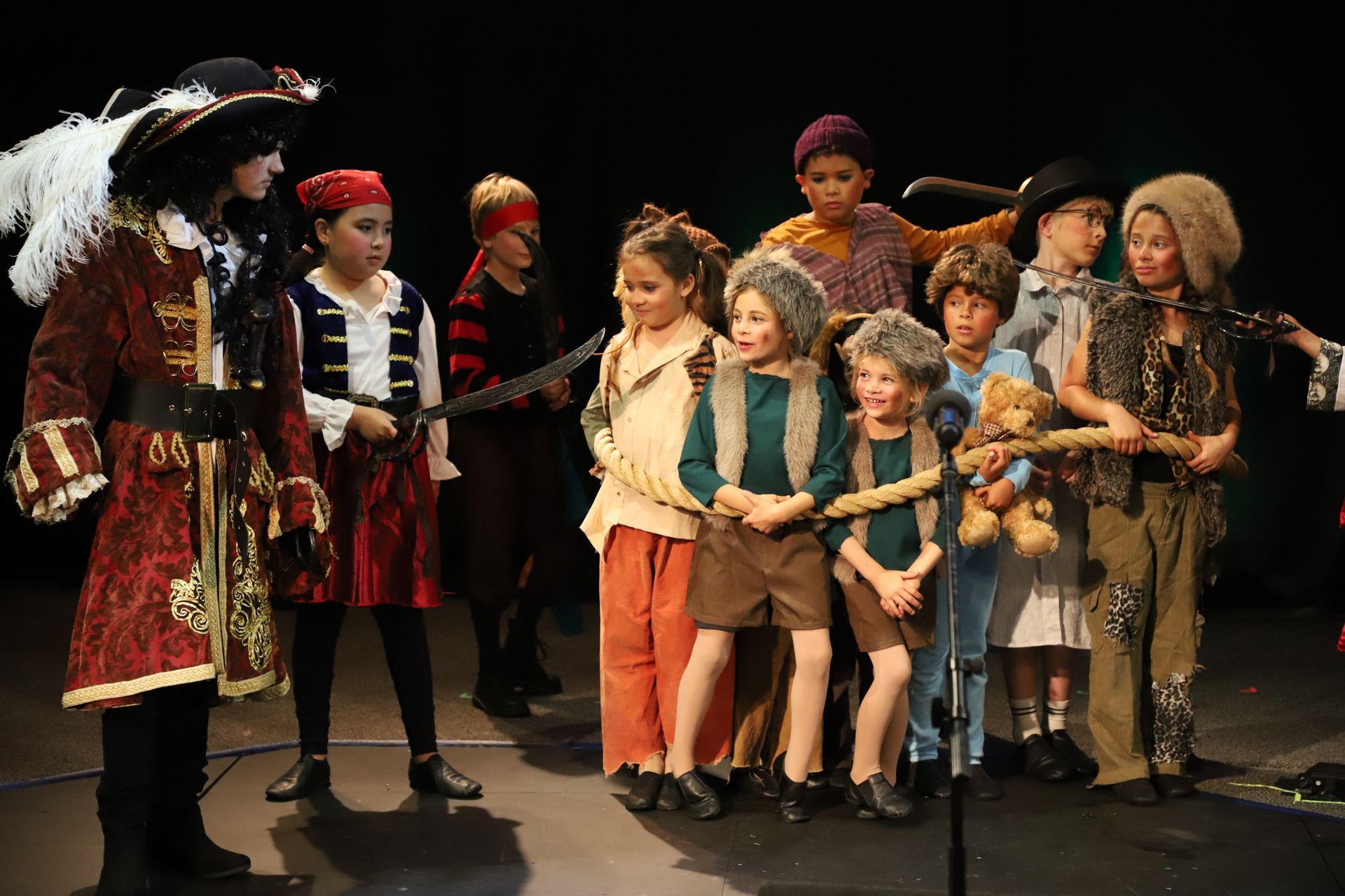 A group of children dressed in pirate costumes are standing on a stage.