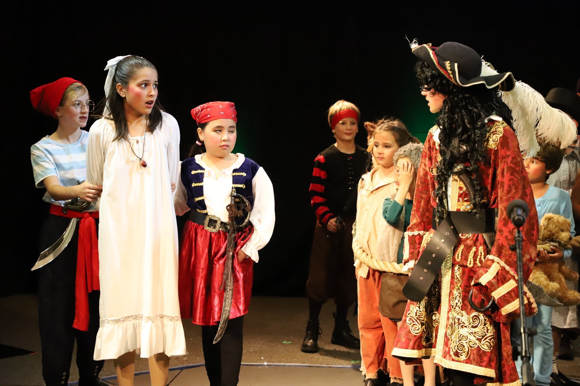 A group of children dressed in pirate costumes are standing on a stage.