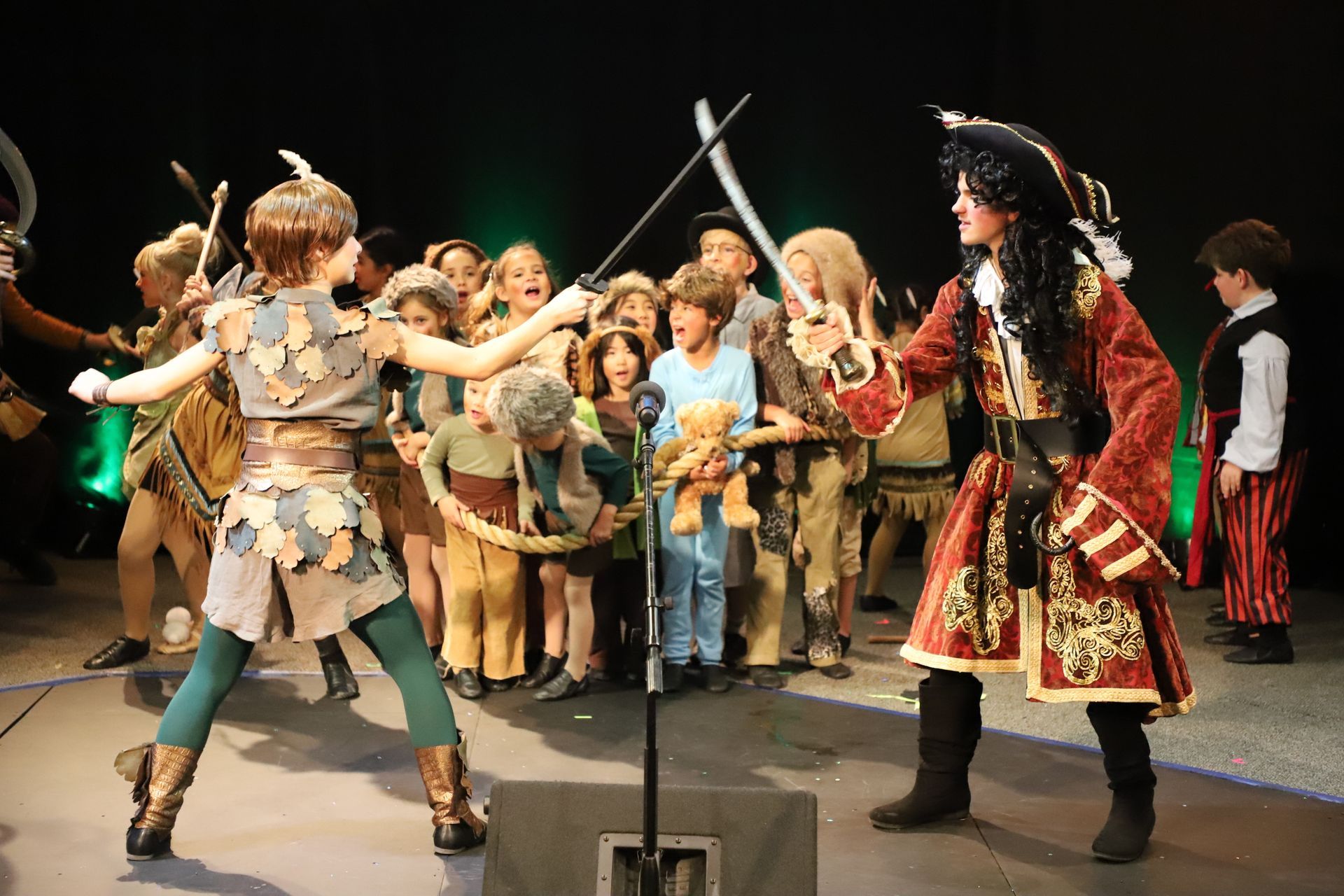Peter pan and hook are fighting on stage in front of a crowd.