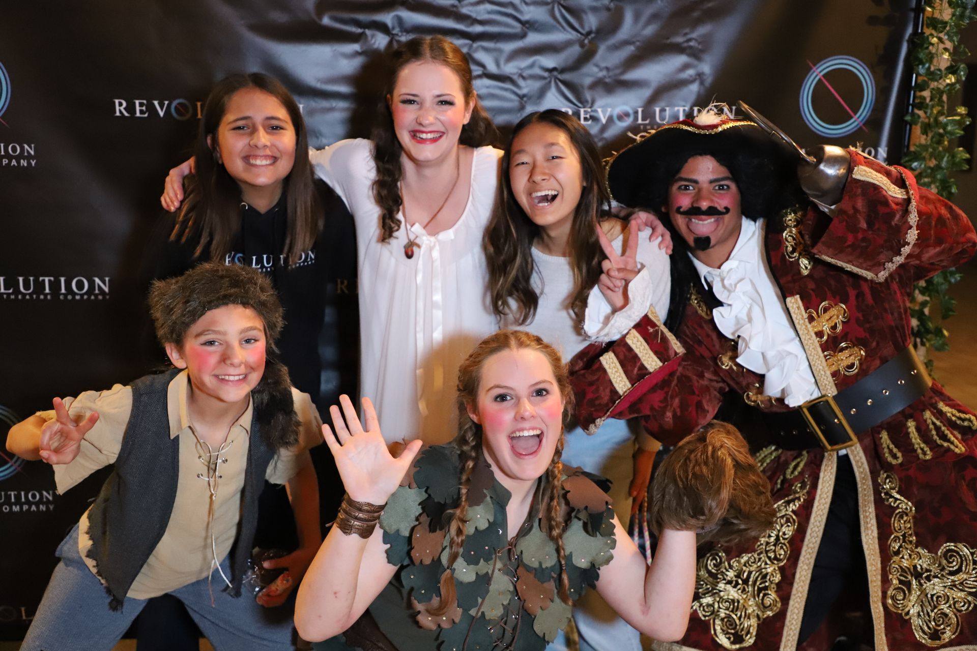 A group of children posing for a picture with a man in a pirate costume.
