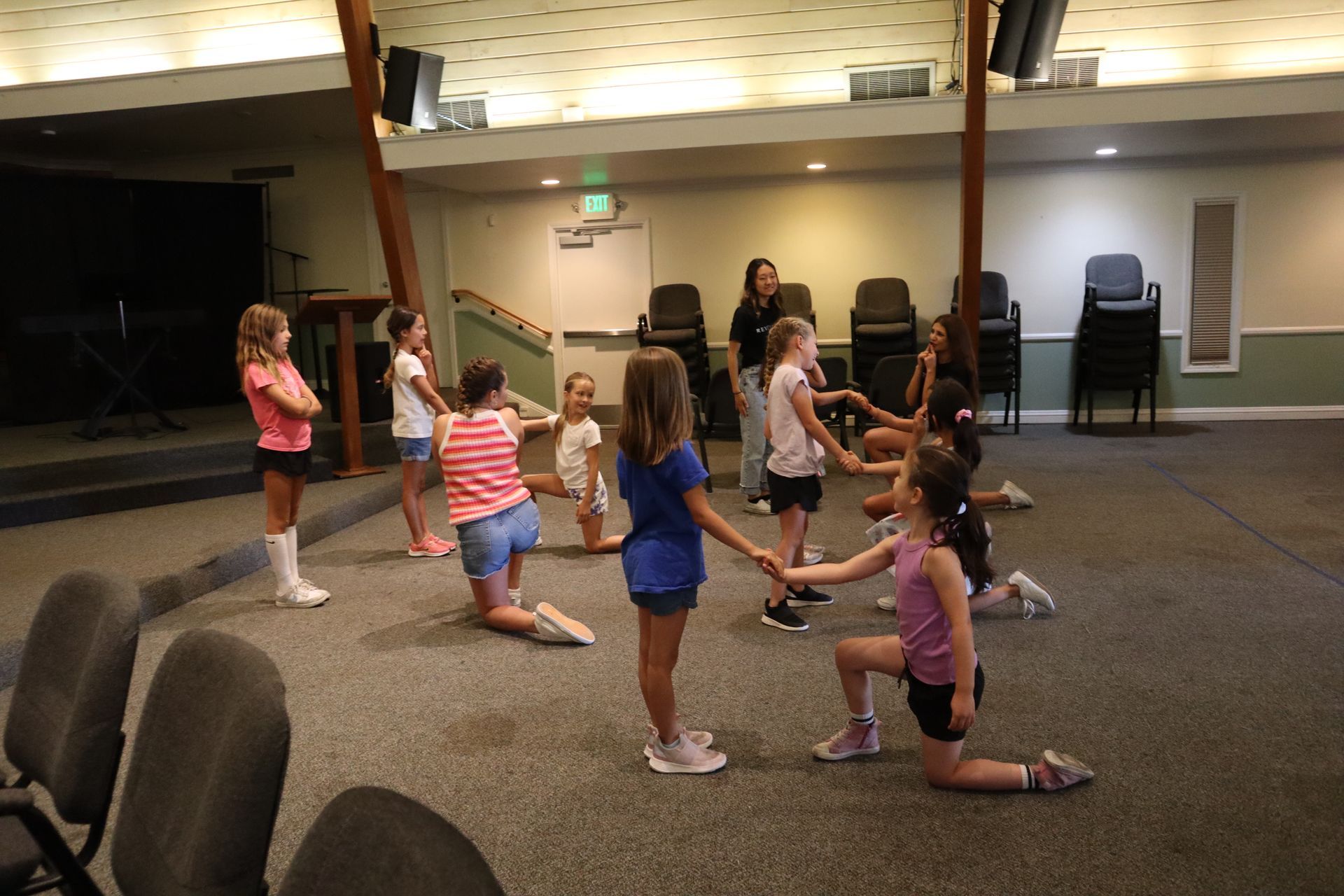 A group of young girls are holding hands in a circle in a room.