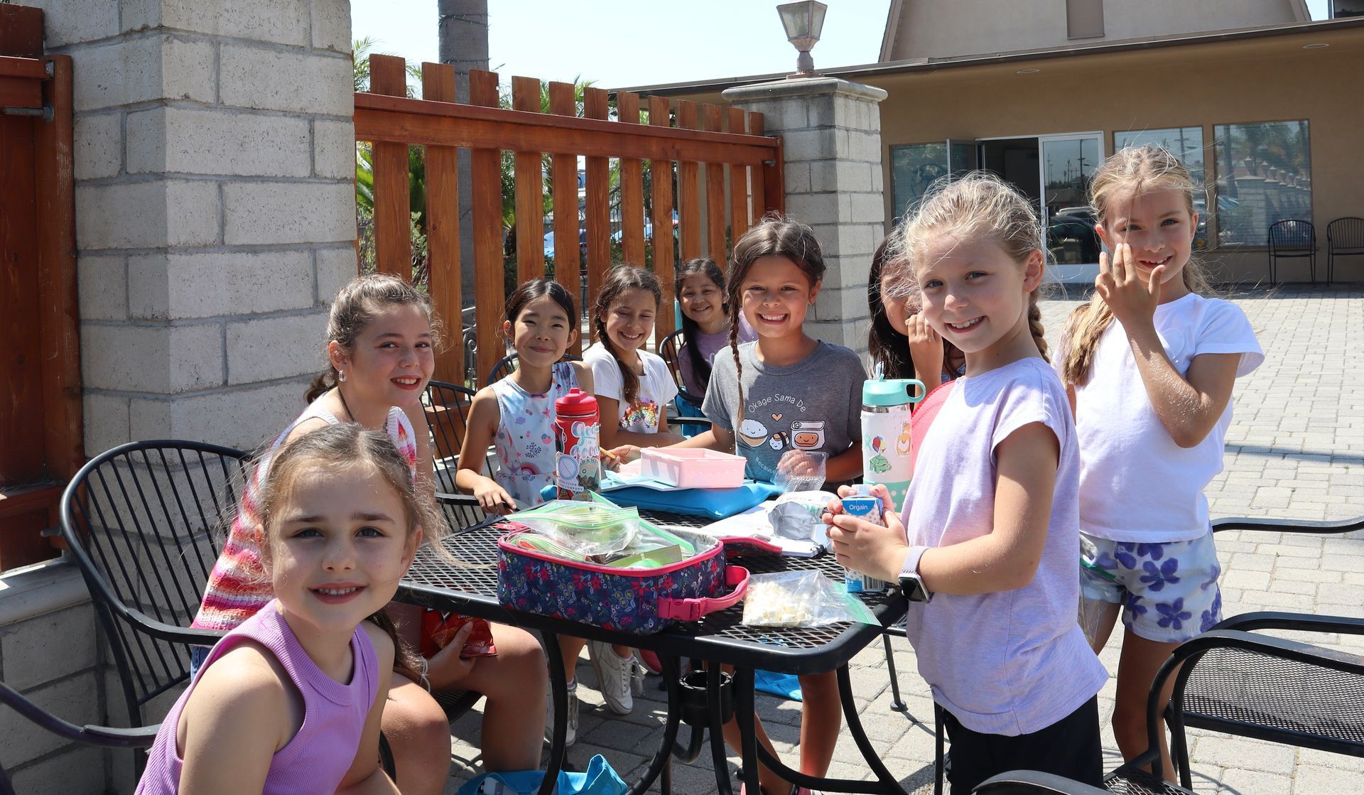 A group of young girls are sitting at a table outside.