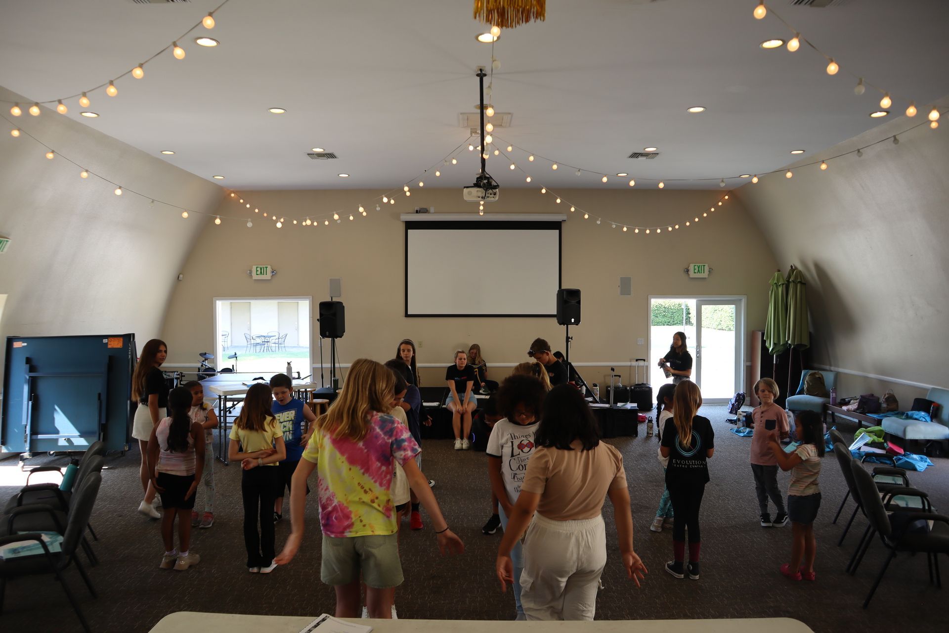 A group of children are dancing in a large room.