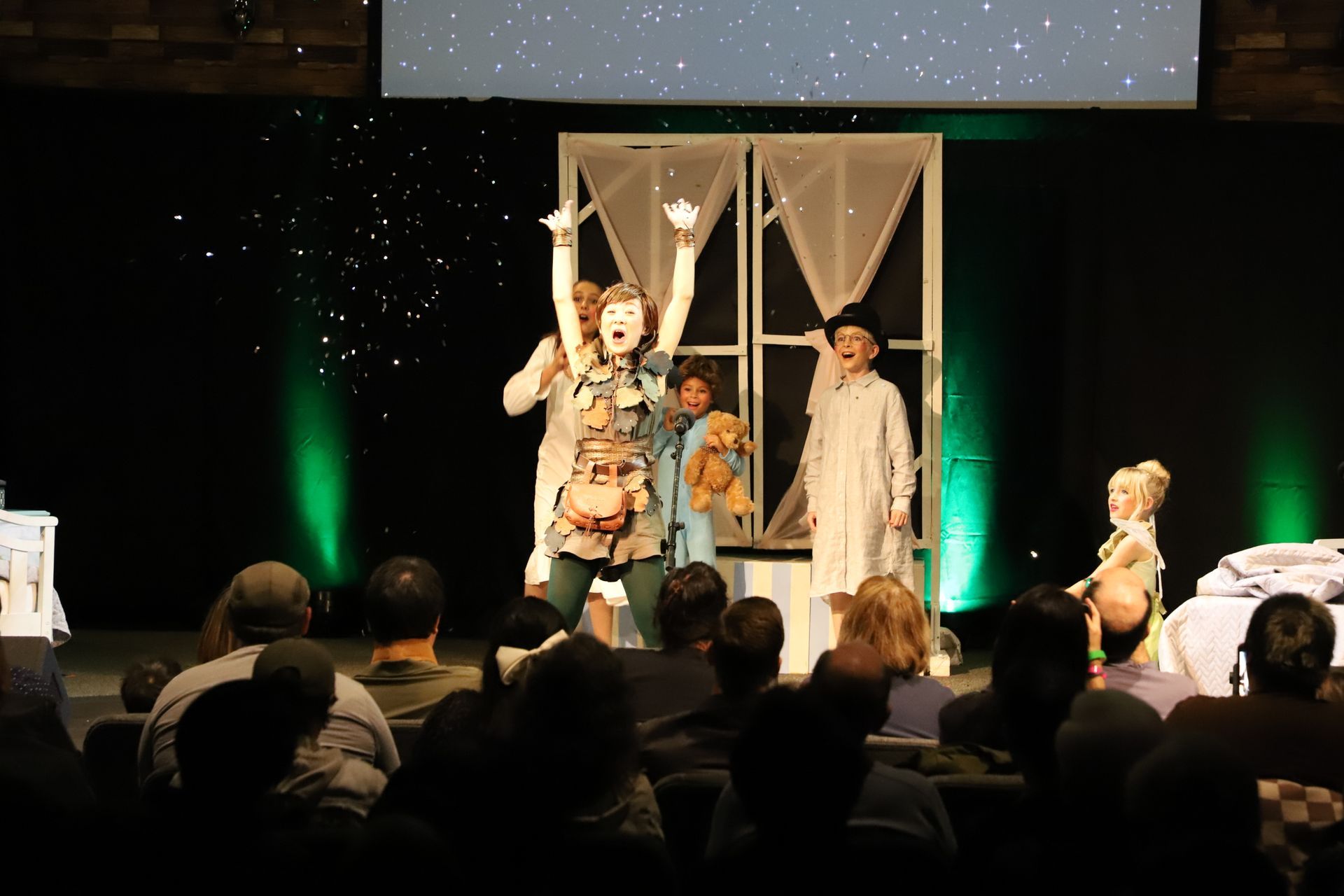 A group of people are standing on a stage with their arms in the air.