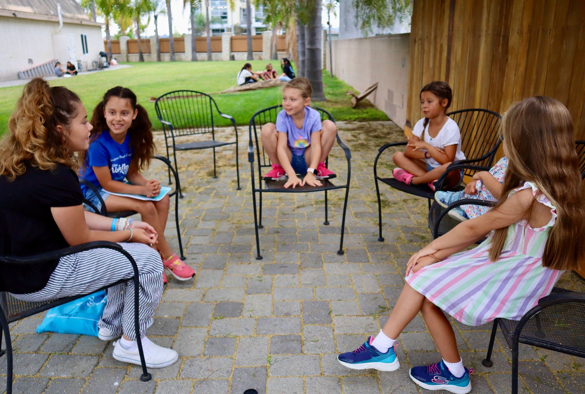 A group of children are sitting in a circle on a patio.