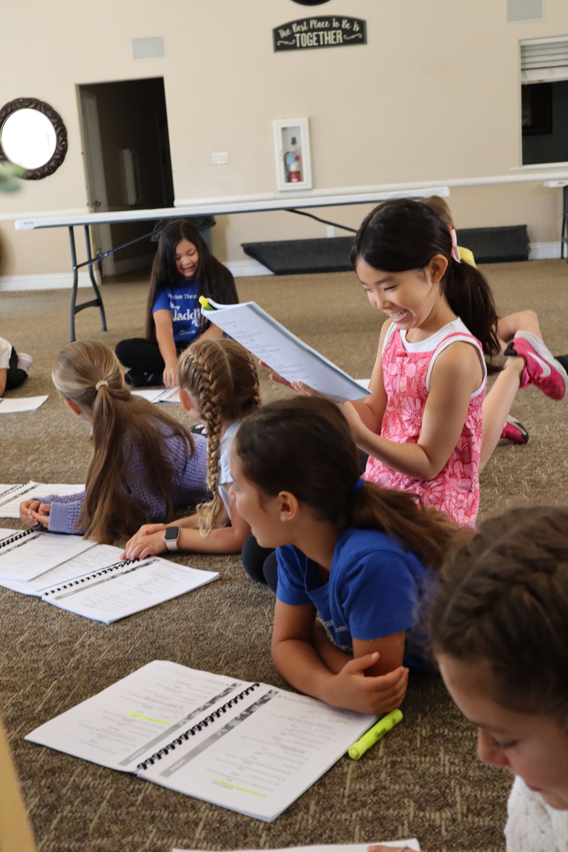 A group of young girls are sitting on the floor reading books.