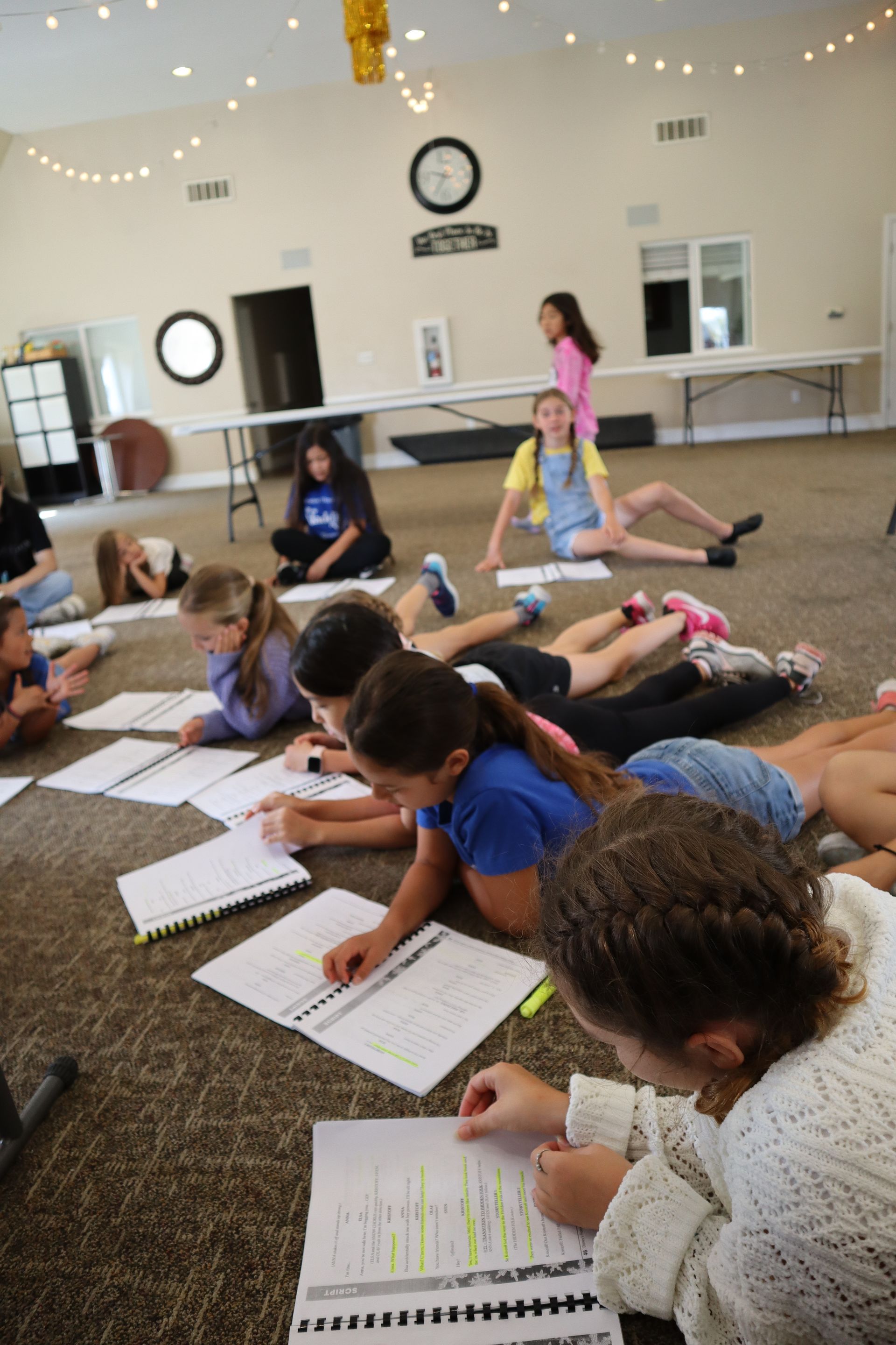 A group of children are laying on the floor writing in notebooks.