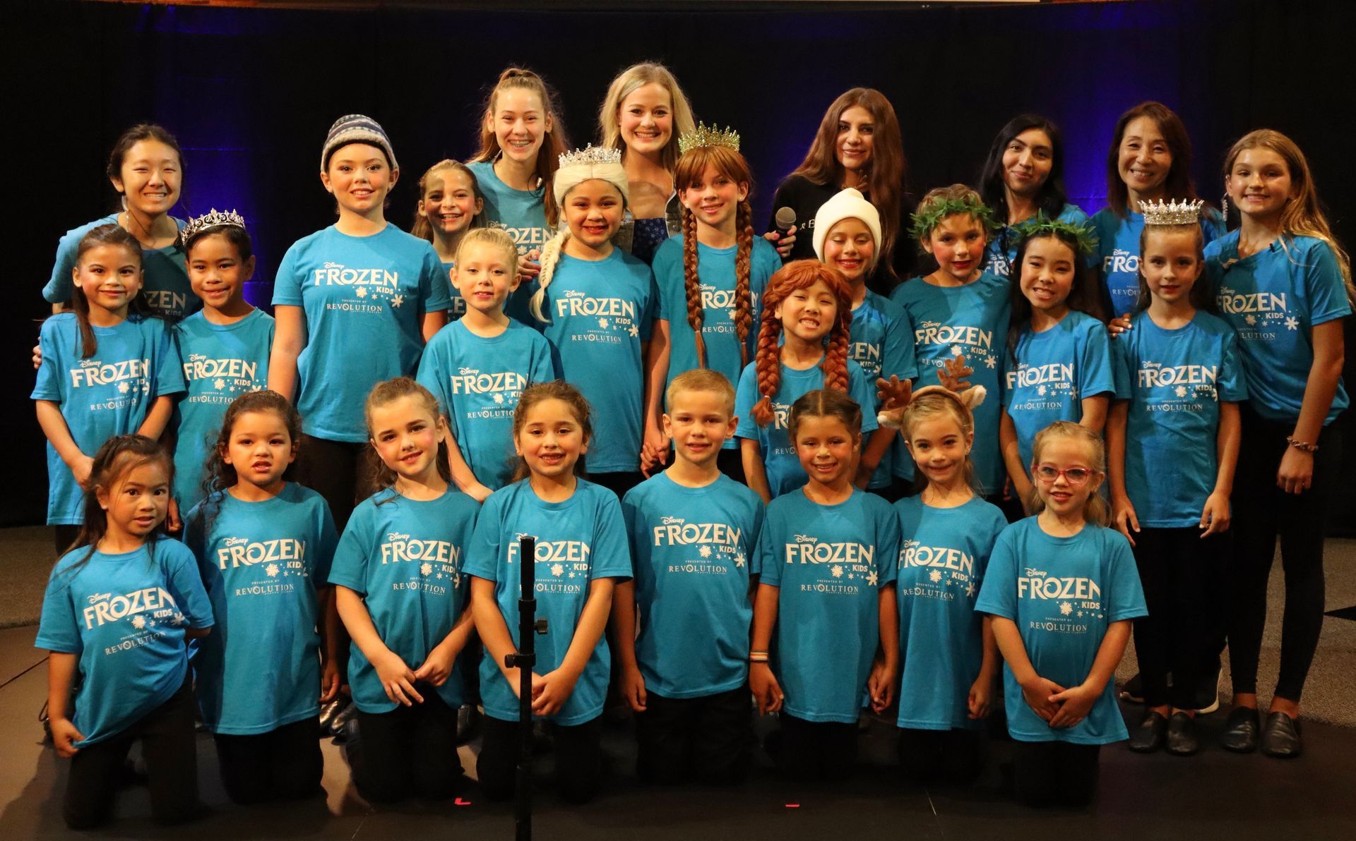 A group of young girls in blue shirts are posing for a picture.