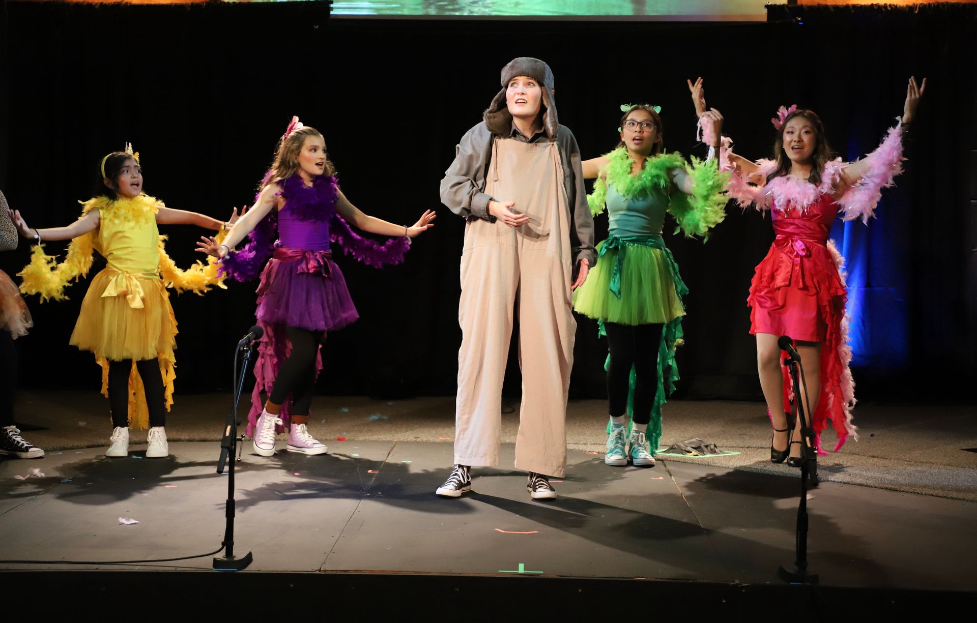 A group of children are standing on a stage in costumes.