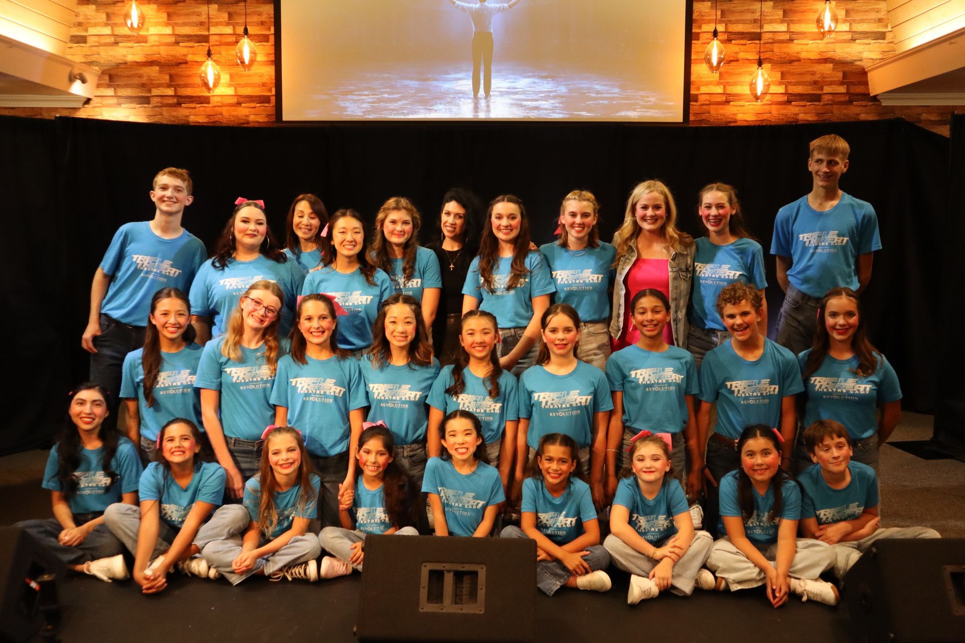 A group of children in blue shirts are posing for a picture.