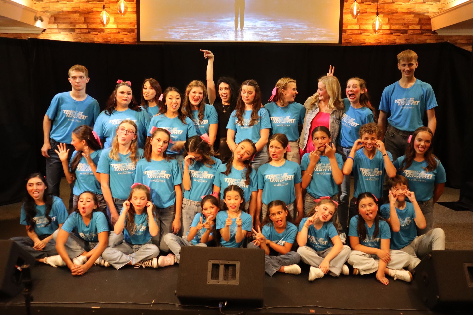 A group of young people are posing for a picture on a stage.