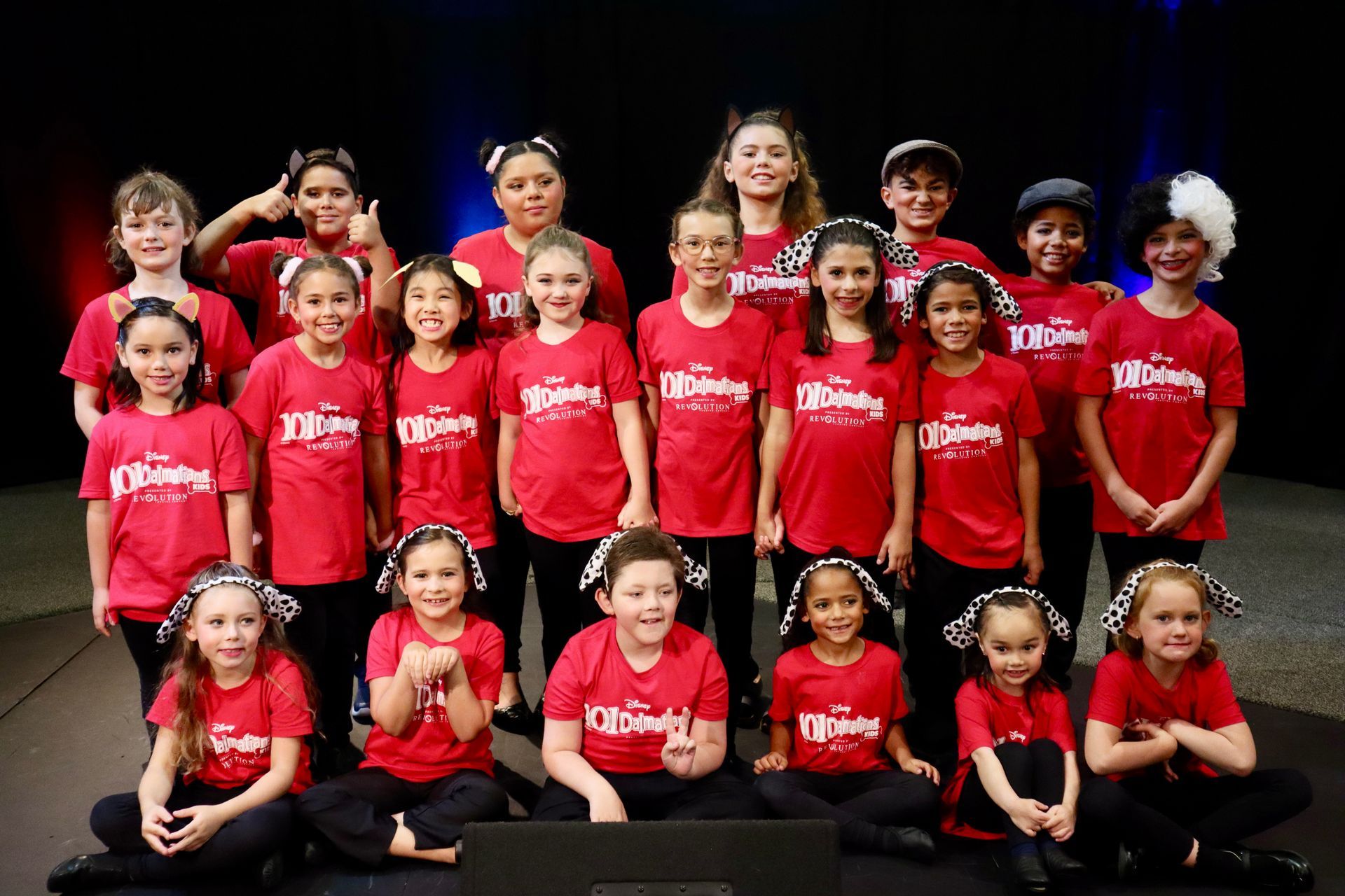 A group of children wearing red shirts and hats are posing for a picture.