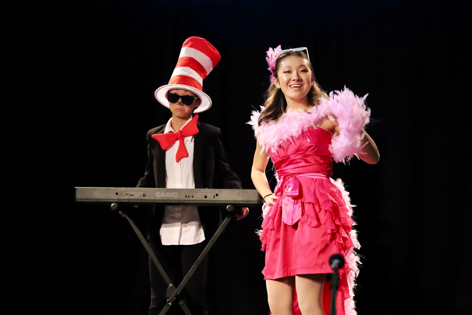 A girl in a pink dress is standing next to a boy in a cat in the hat.