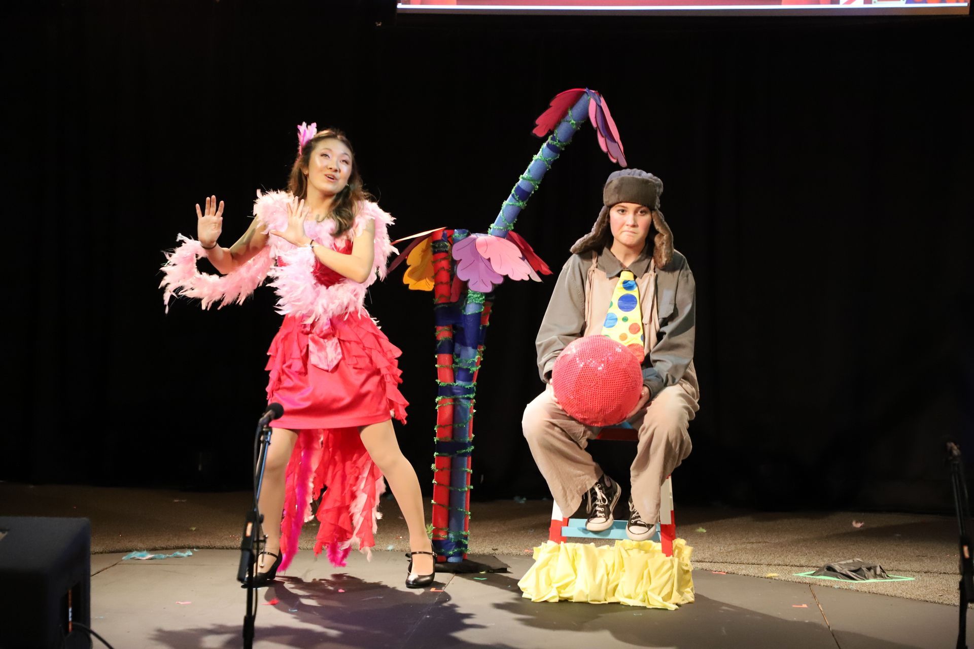 A woman in a pink dress is dancing next to a man in a clown costume.