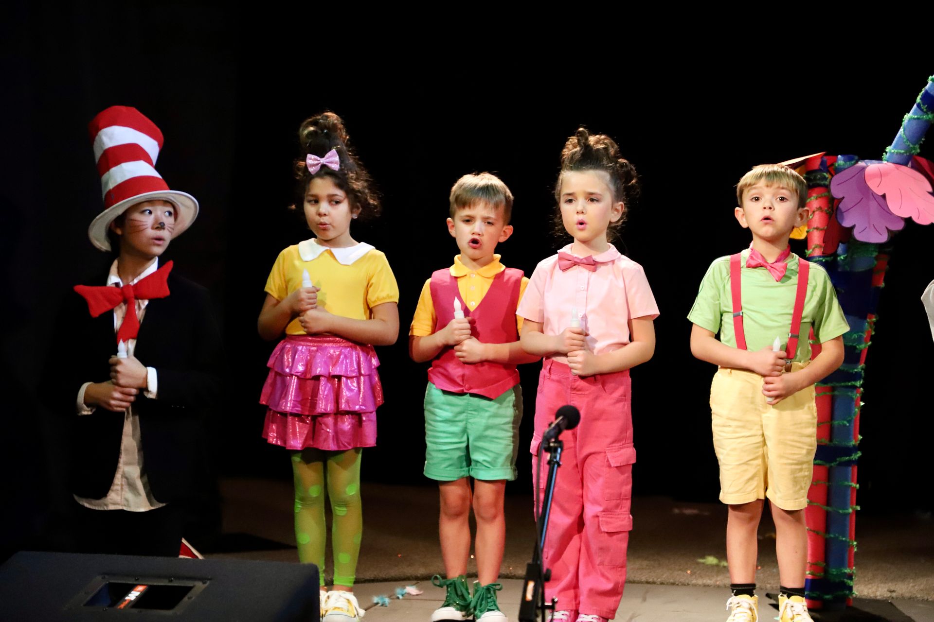 A group of children singing into microphones on a stage