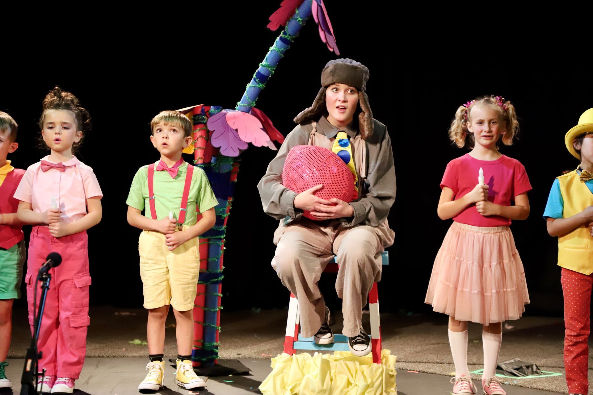 A group of children are standing in front of a microphone on a stage.
