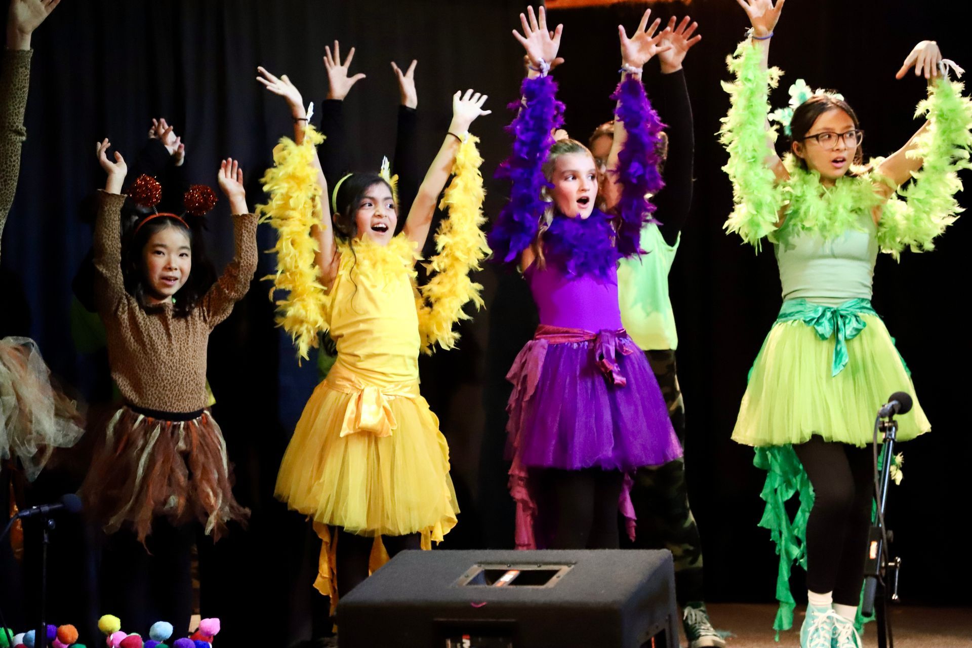 A group of young girls are standing on a stage with their hands in the air.