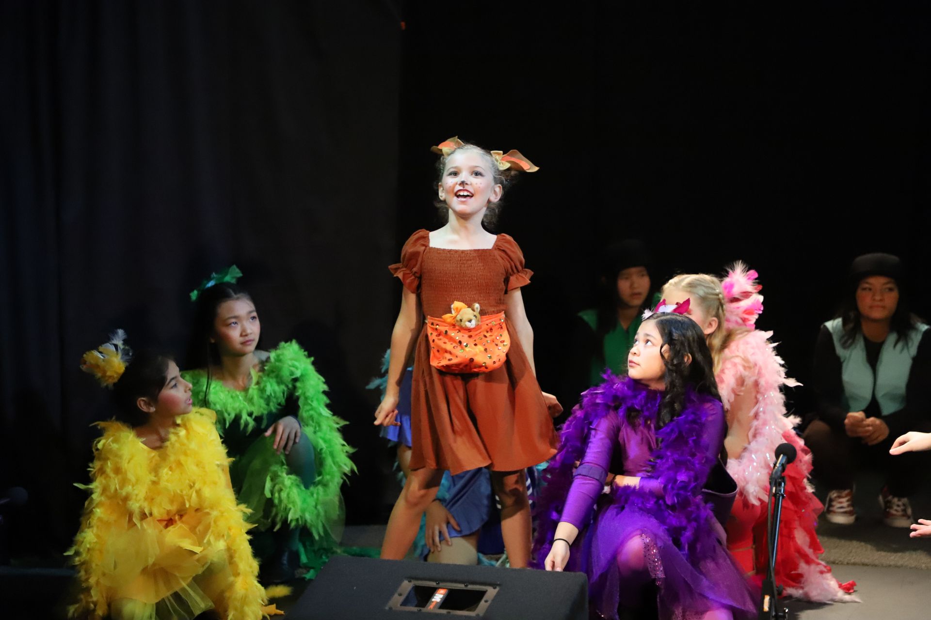 A group of children dressed in costumes are standing on a stage.