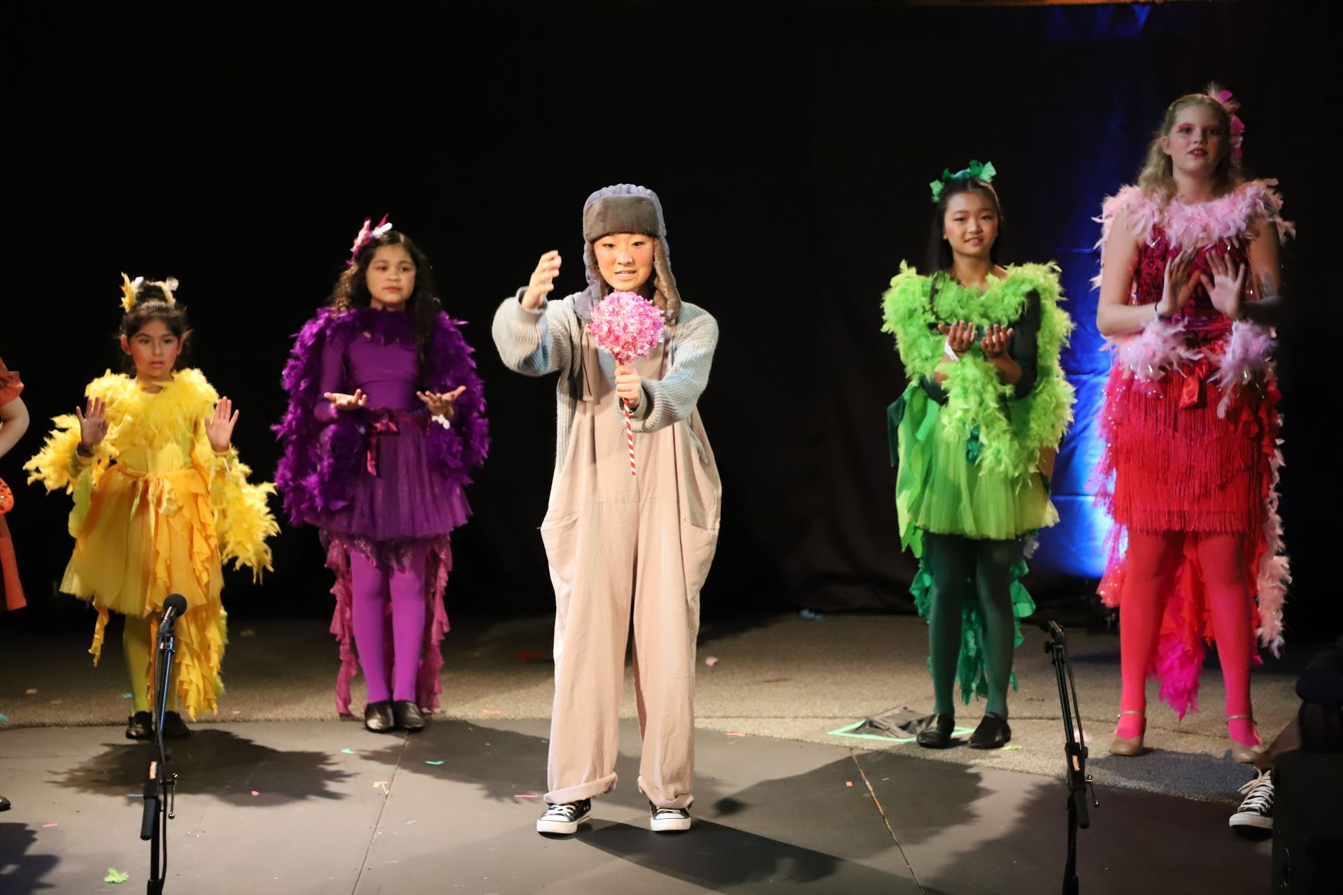 A group of children in colorful costumes are standing on a stage.