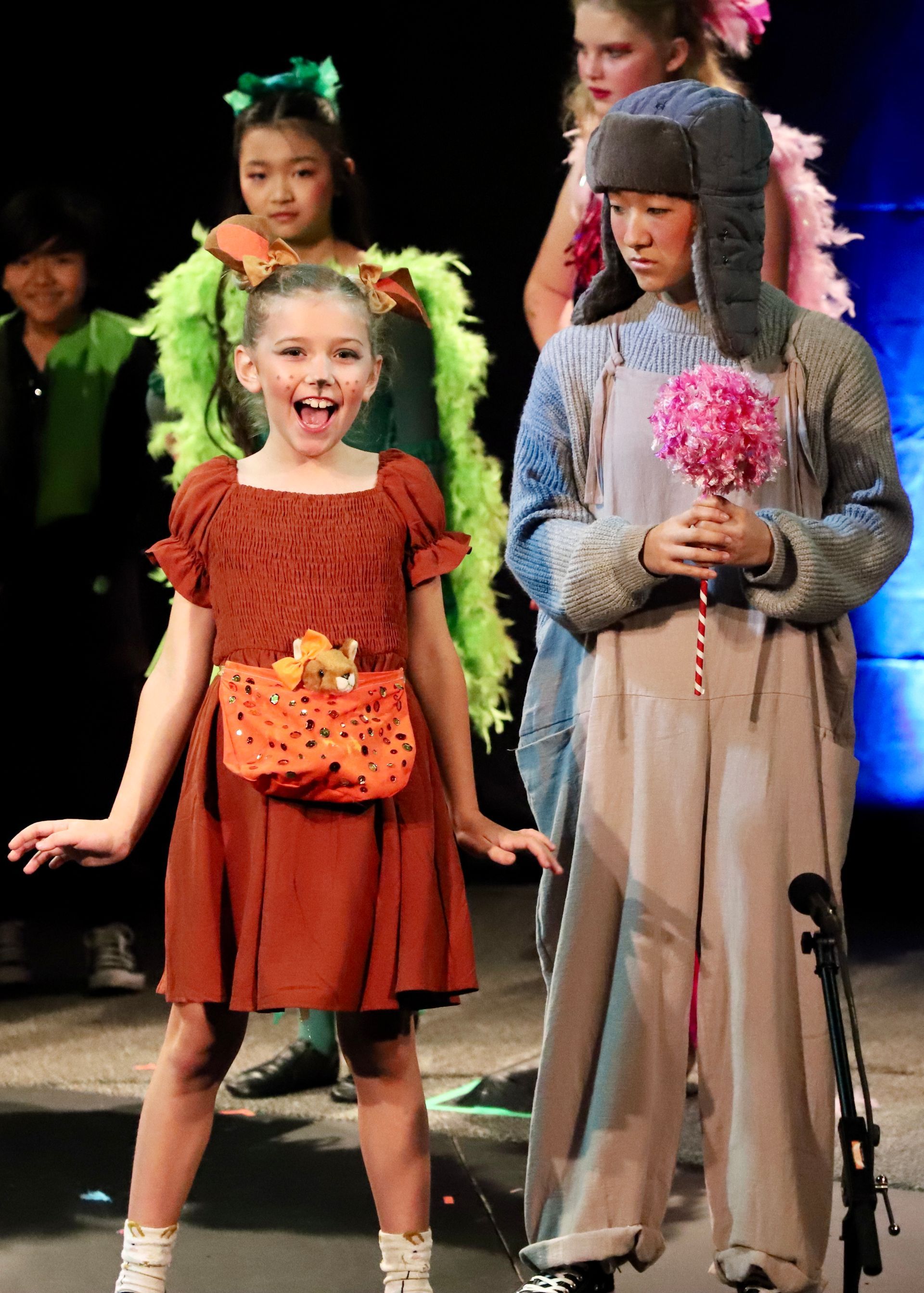 A group of children dressed in costumes are standing on a stage.