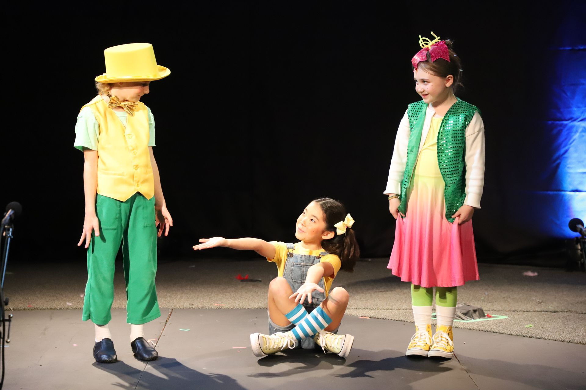 A group of children dressed in colorful costumes are on a stage.