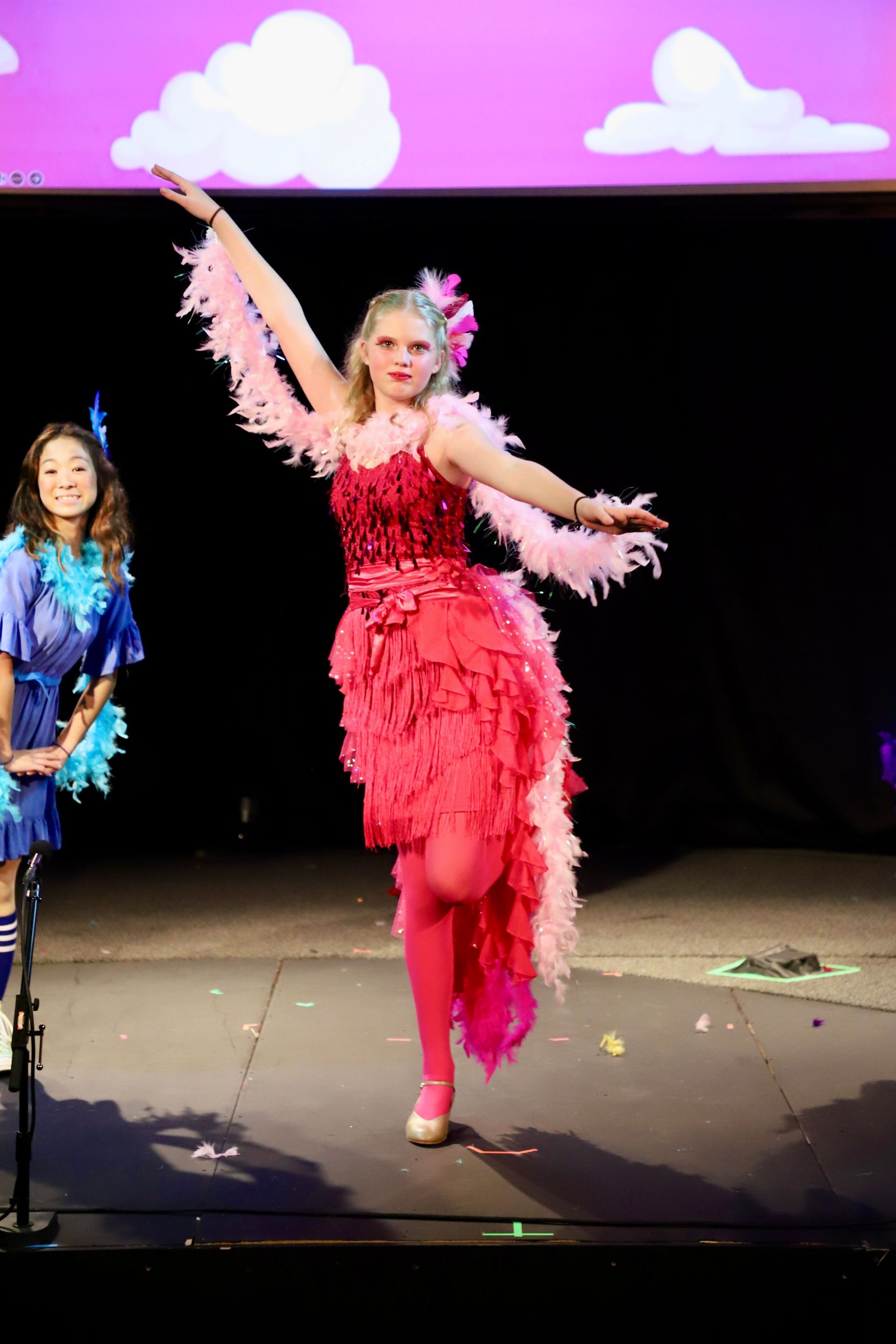 A woman in a pink dress is dancing on a stage.