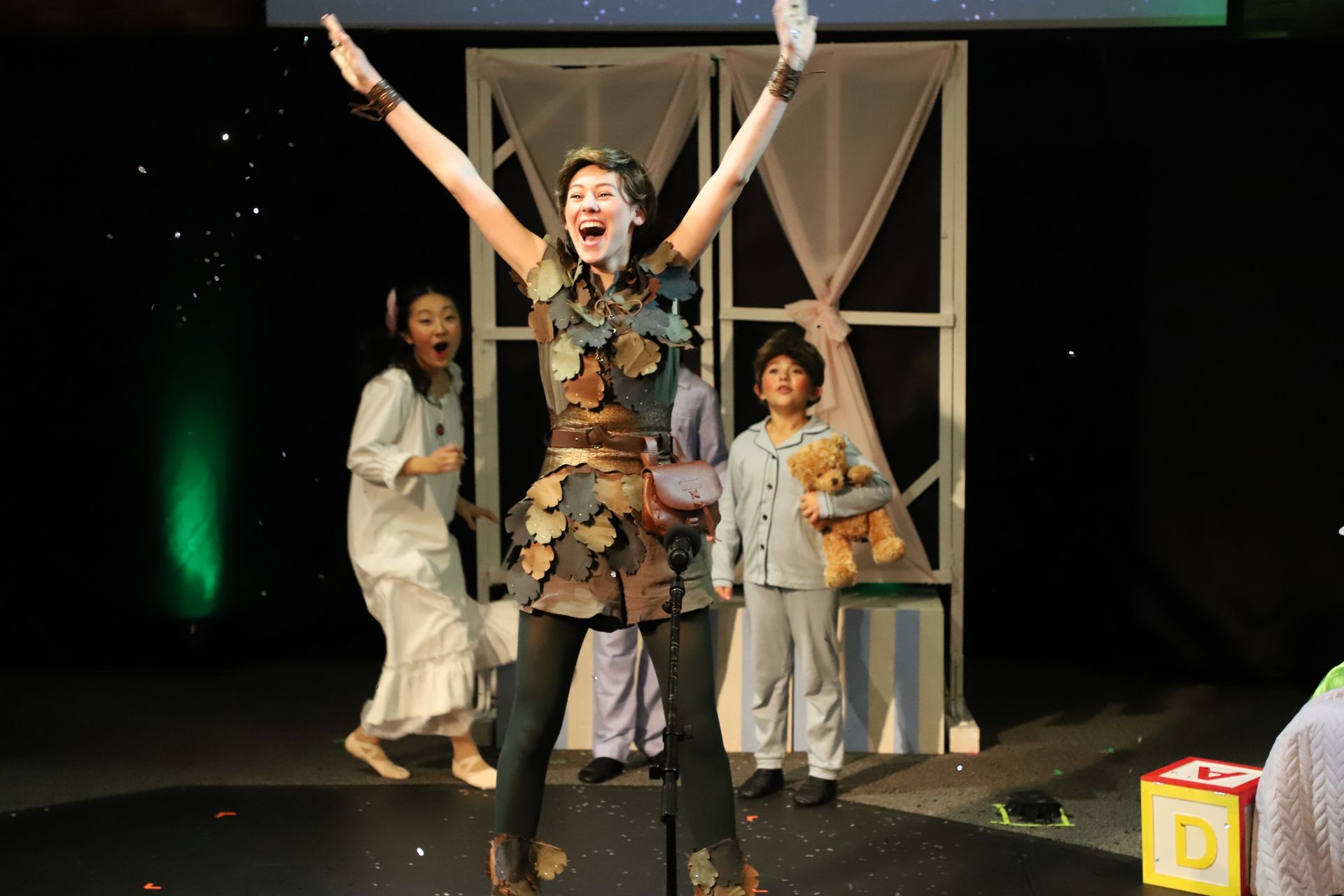 A woman is standing on a stage with her arms in the air.