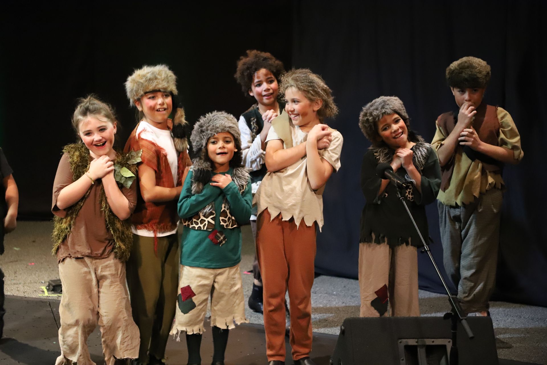 A group of children are standing in front of a microphone on a stage.