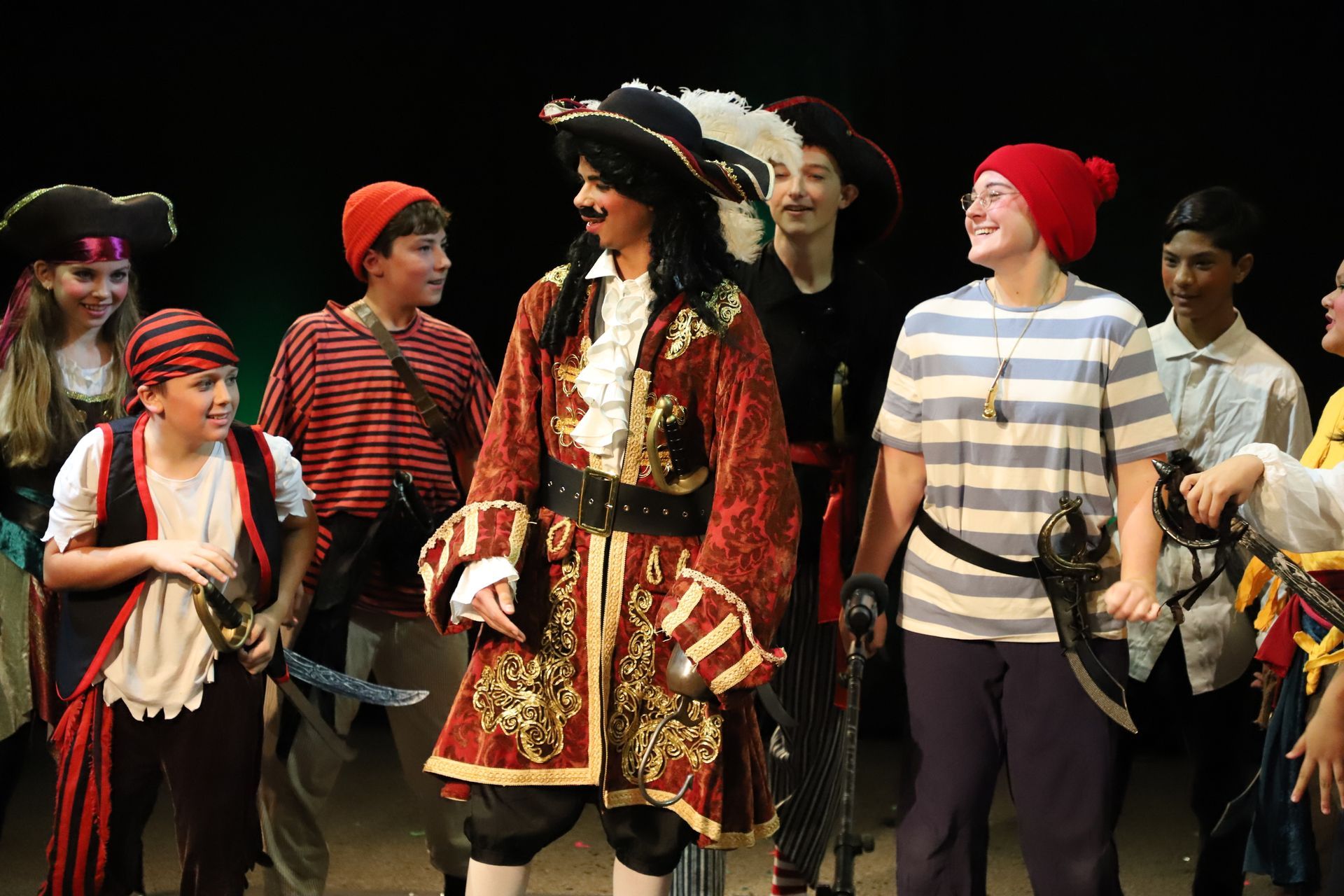 A group of children dressed in pirate costumes are standing on a stage.