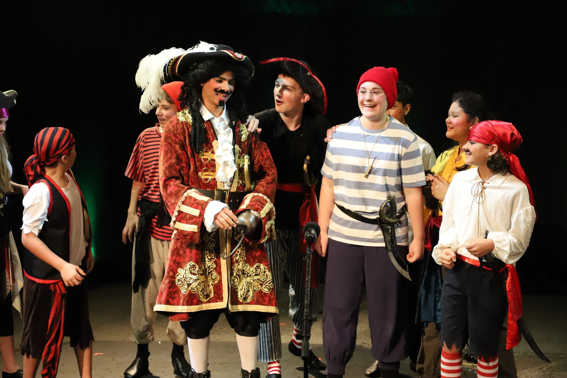 A group of children dressed in pirate costumes are standing on a stage.