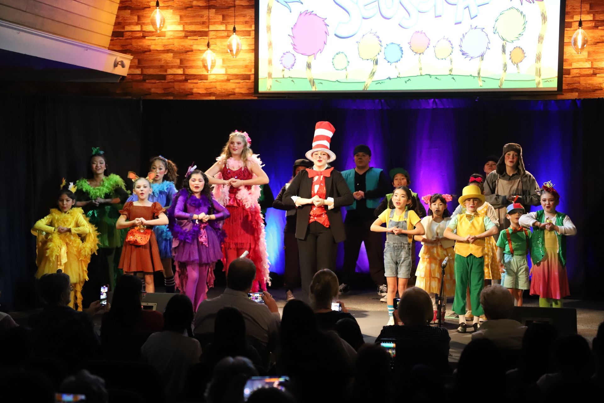 A group of children are standing on a stage in front of a crowd.