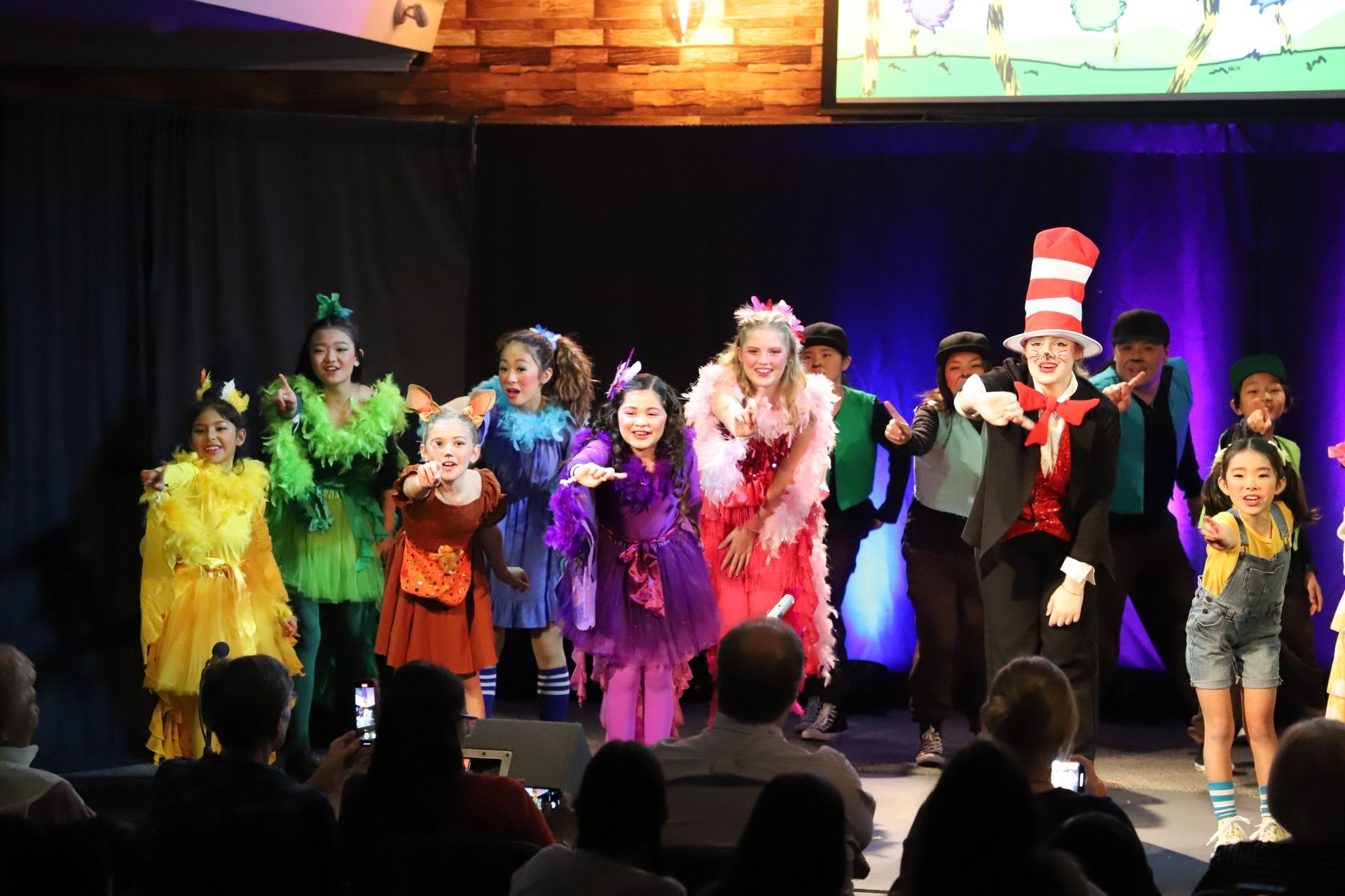 A group of children are standing on a stage in front of a crowd.