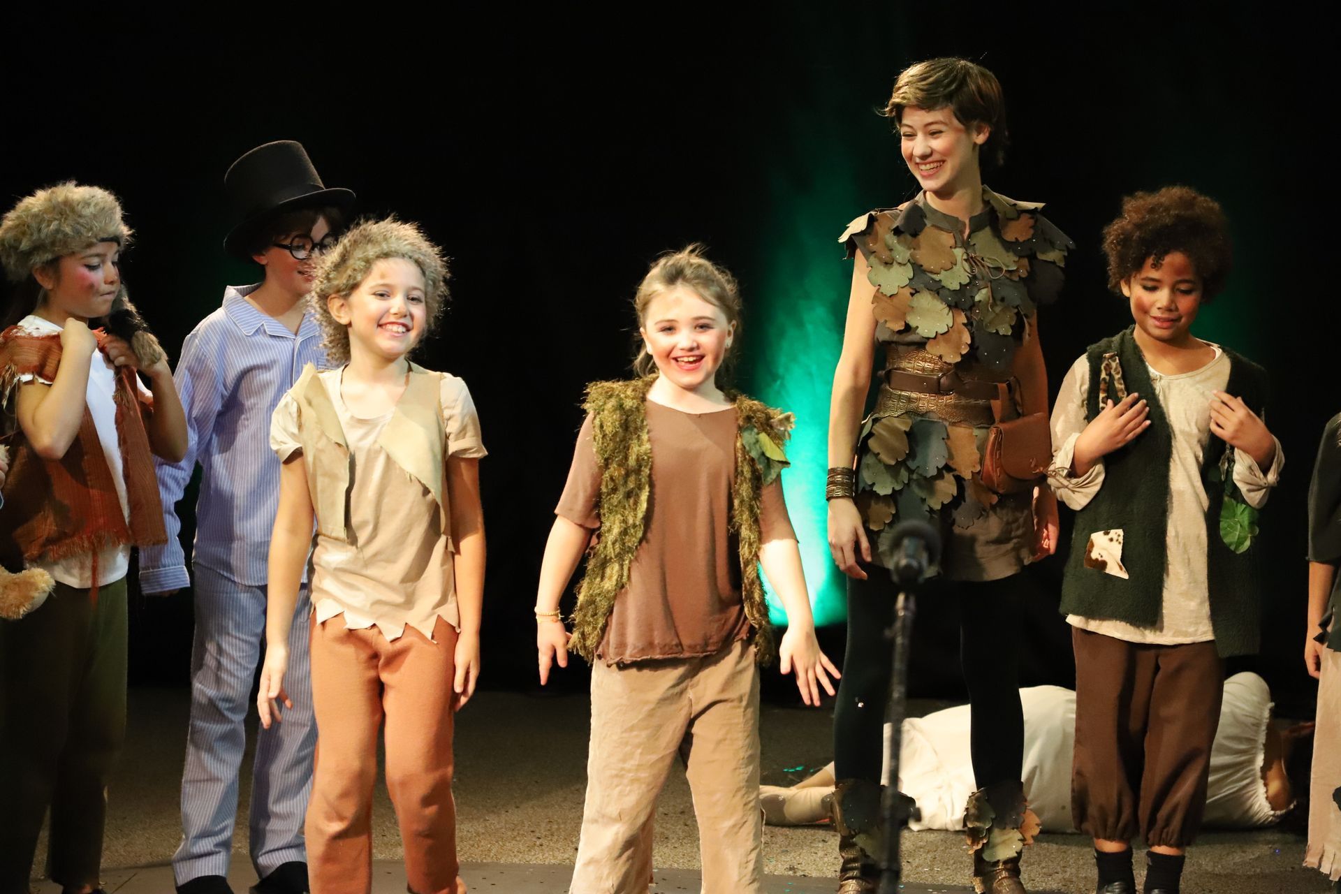 A group of children dressed in costumes are standing on a stage.