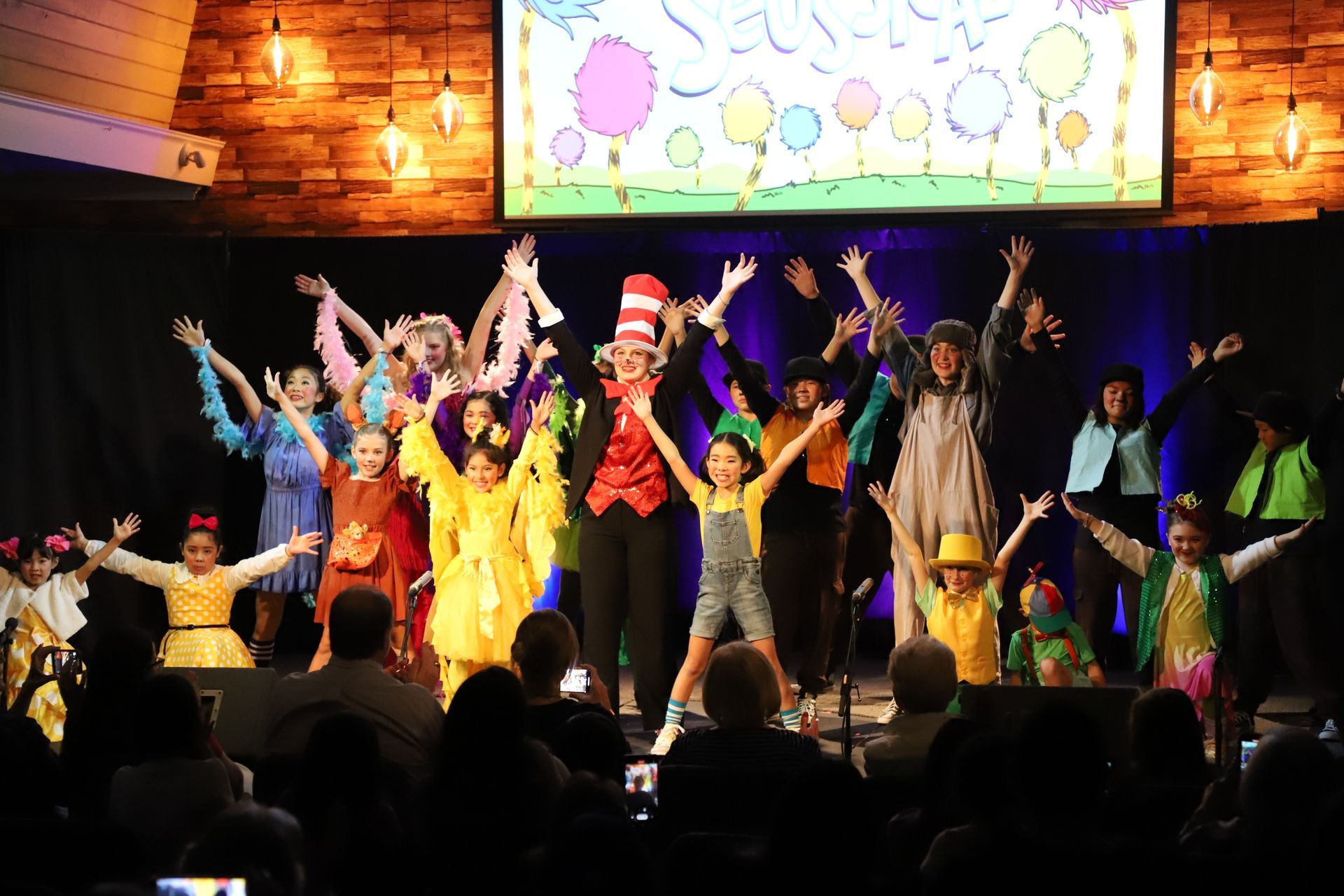 A group of children are dancing on a stage in front of a crowd.