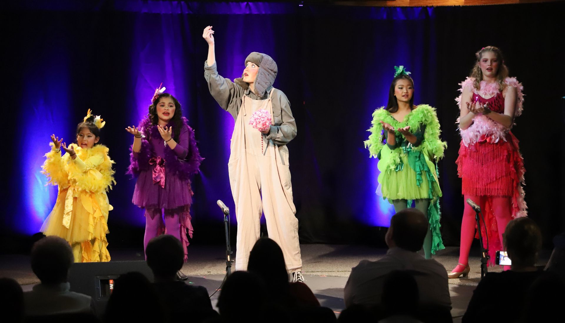 A group of people in costumes are standing on a stage in front of a crowd.