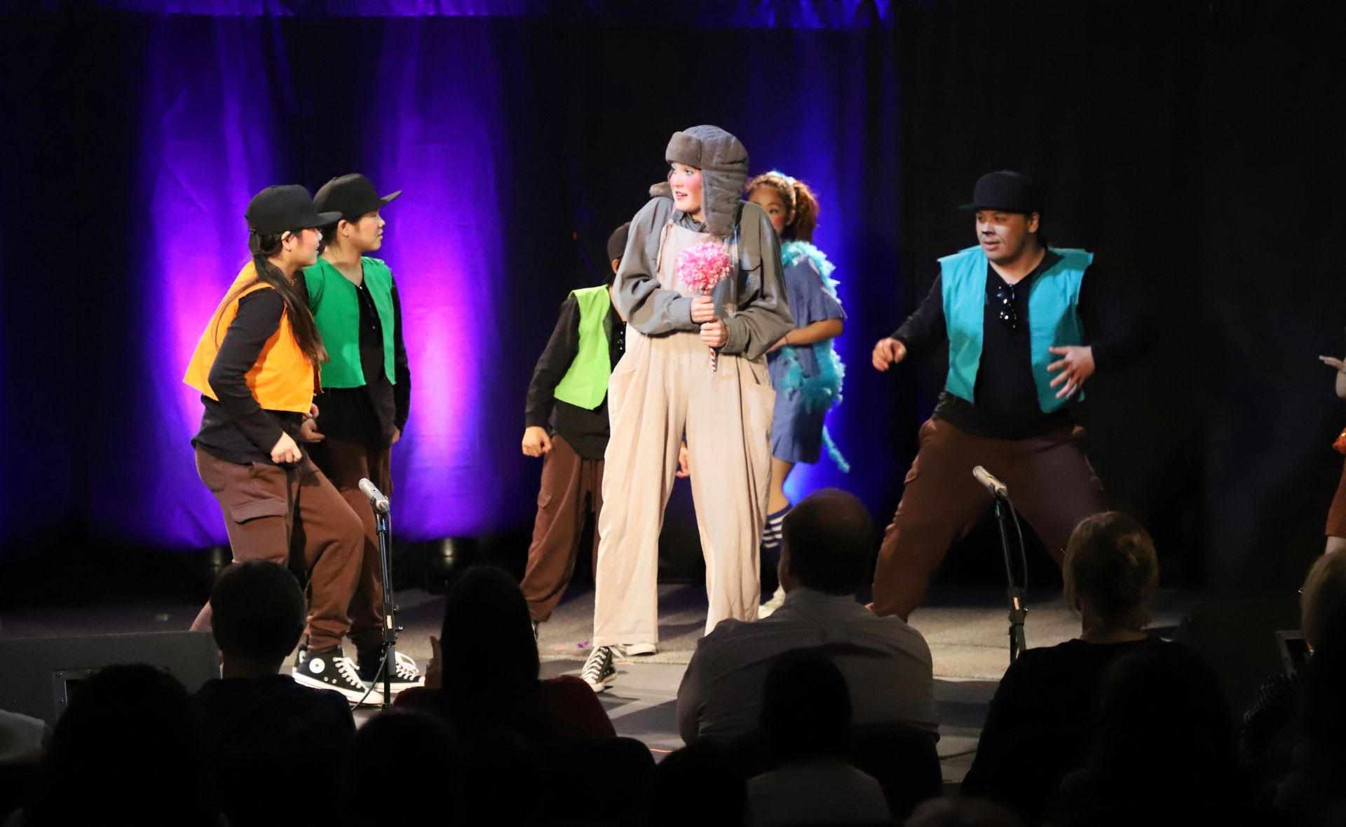 A group of people are dancing on a stage in front of a crowd.