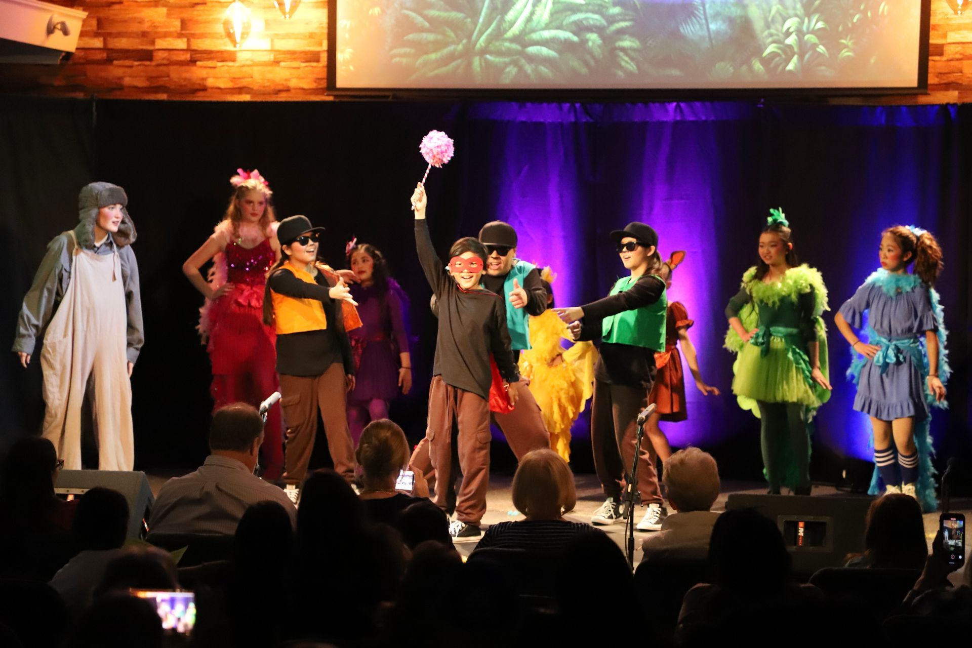 A group of children are dancing on a stage in front of a crowd.