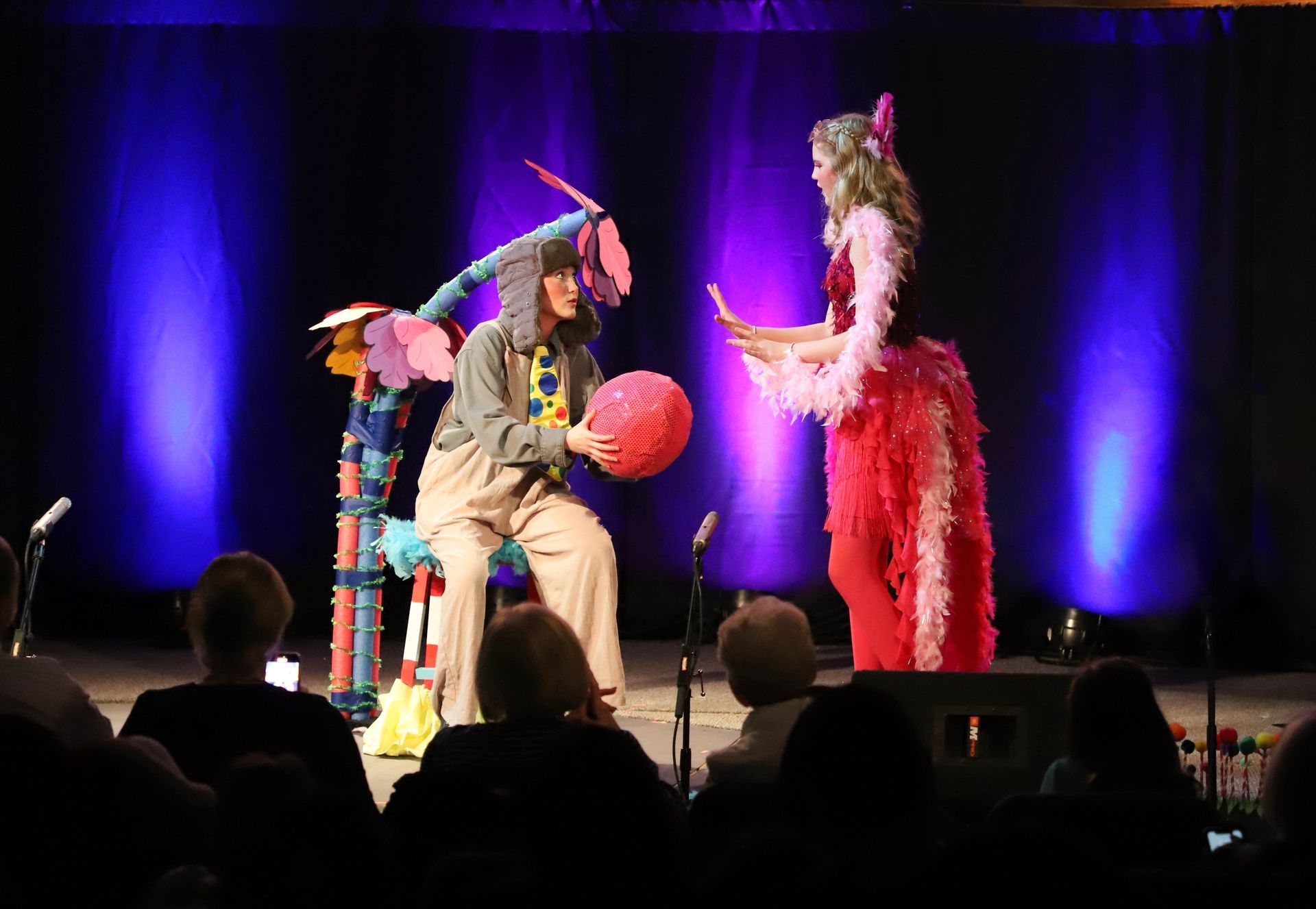 A woman in a pink dress is standing next to a man in a costume on a stage.
