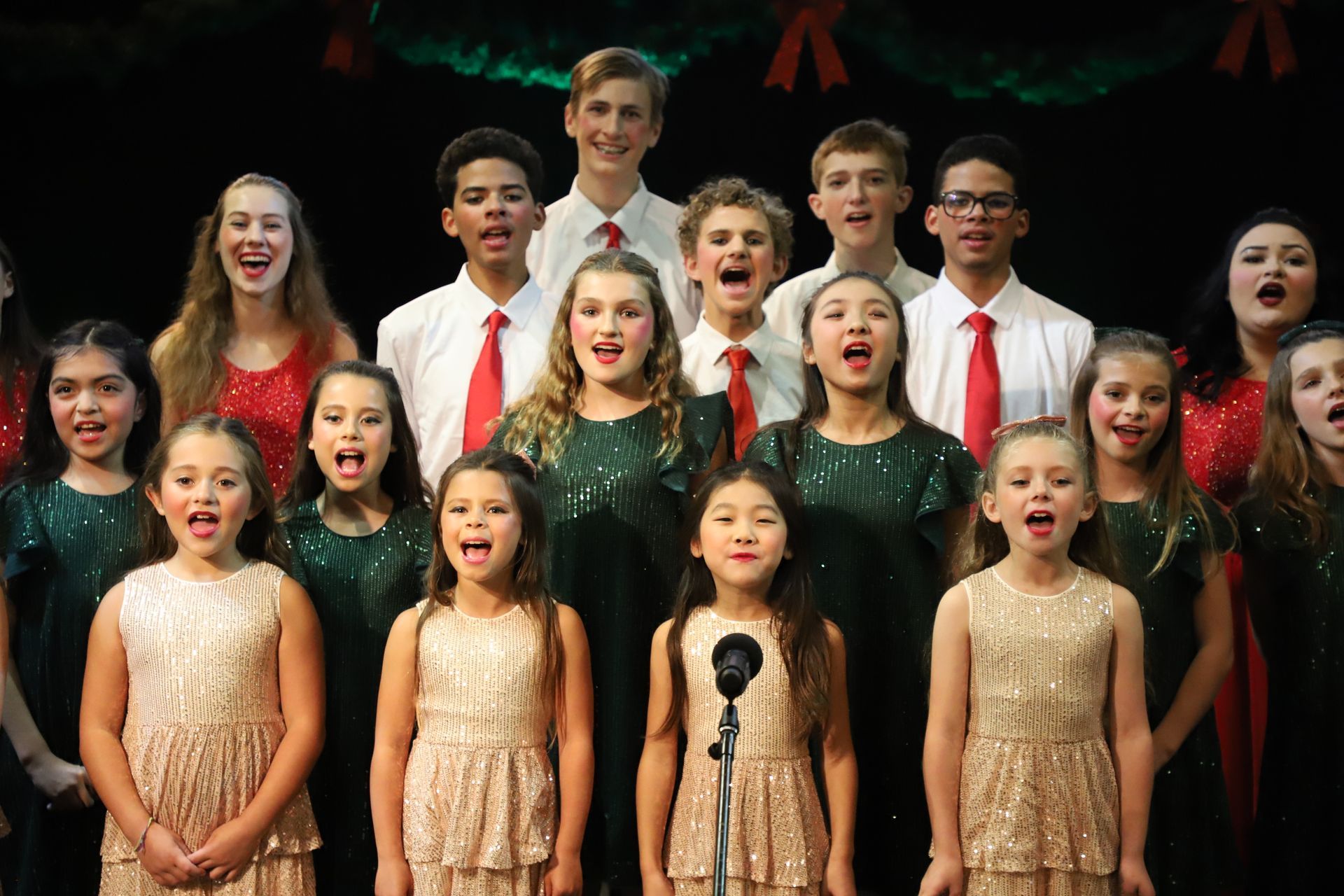 A group of children are singing in a choir on a stage.