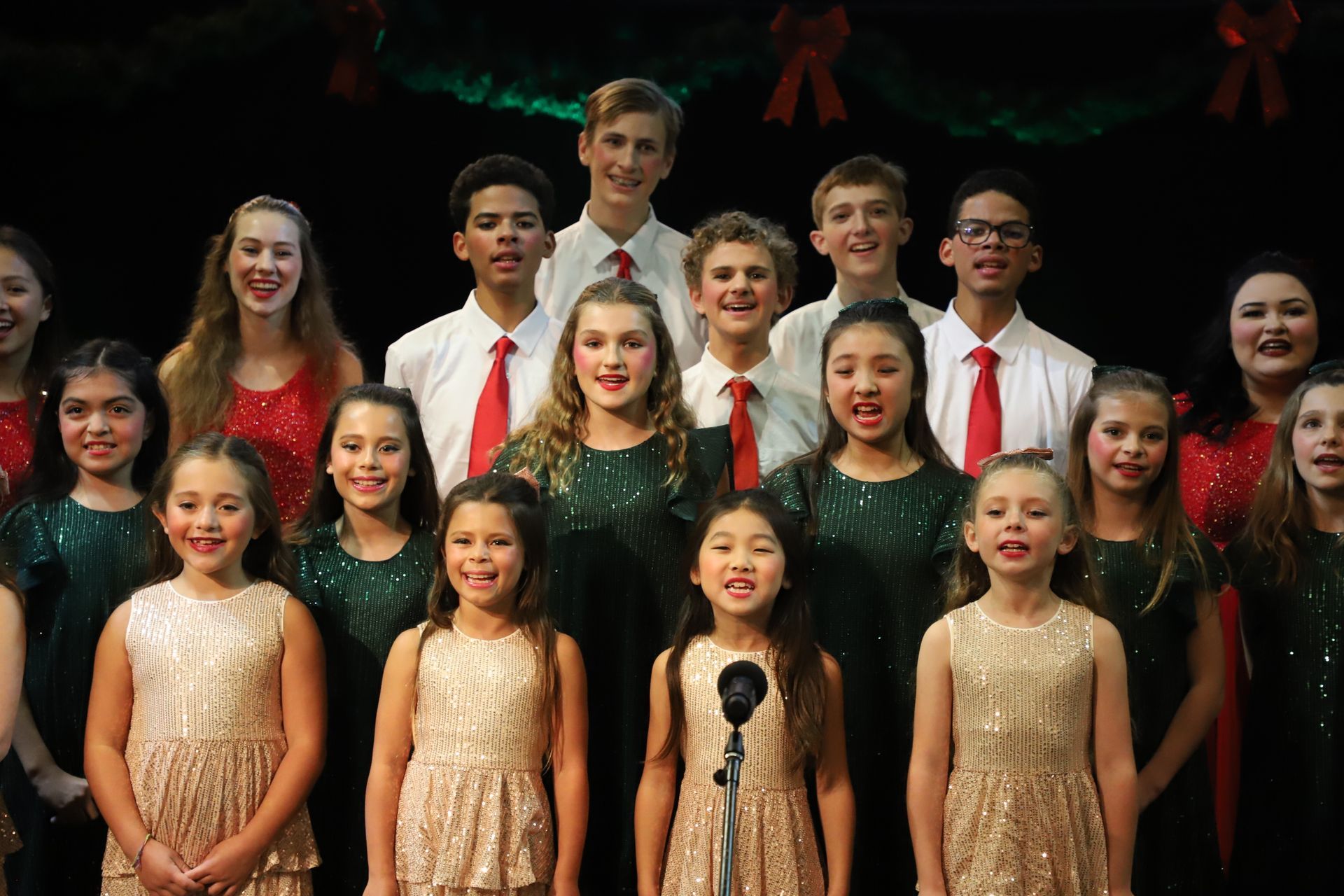 A group of young people are singing in a choir on a stage.
