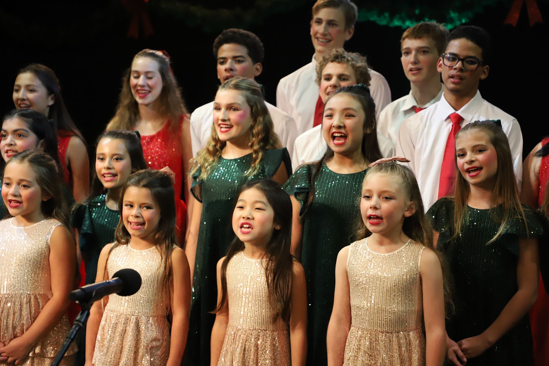 A group of children are singing into microphones on a stage.