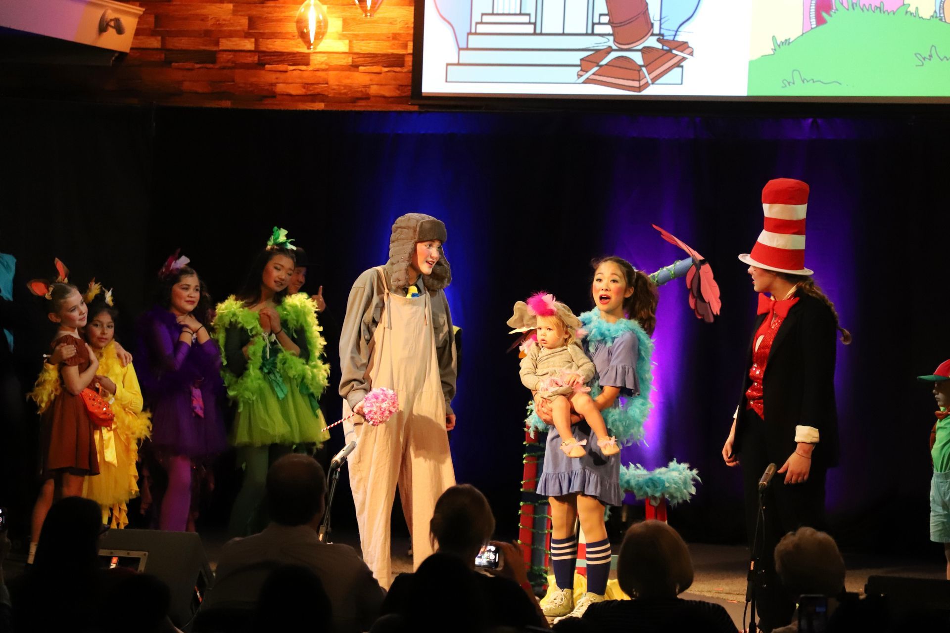 A group of people in costumes are standing on a stage.