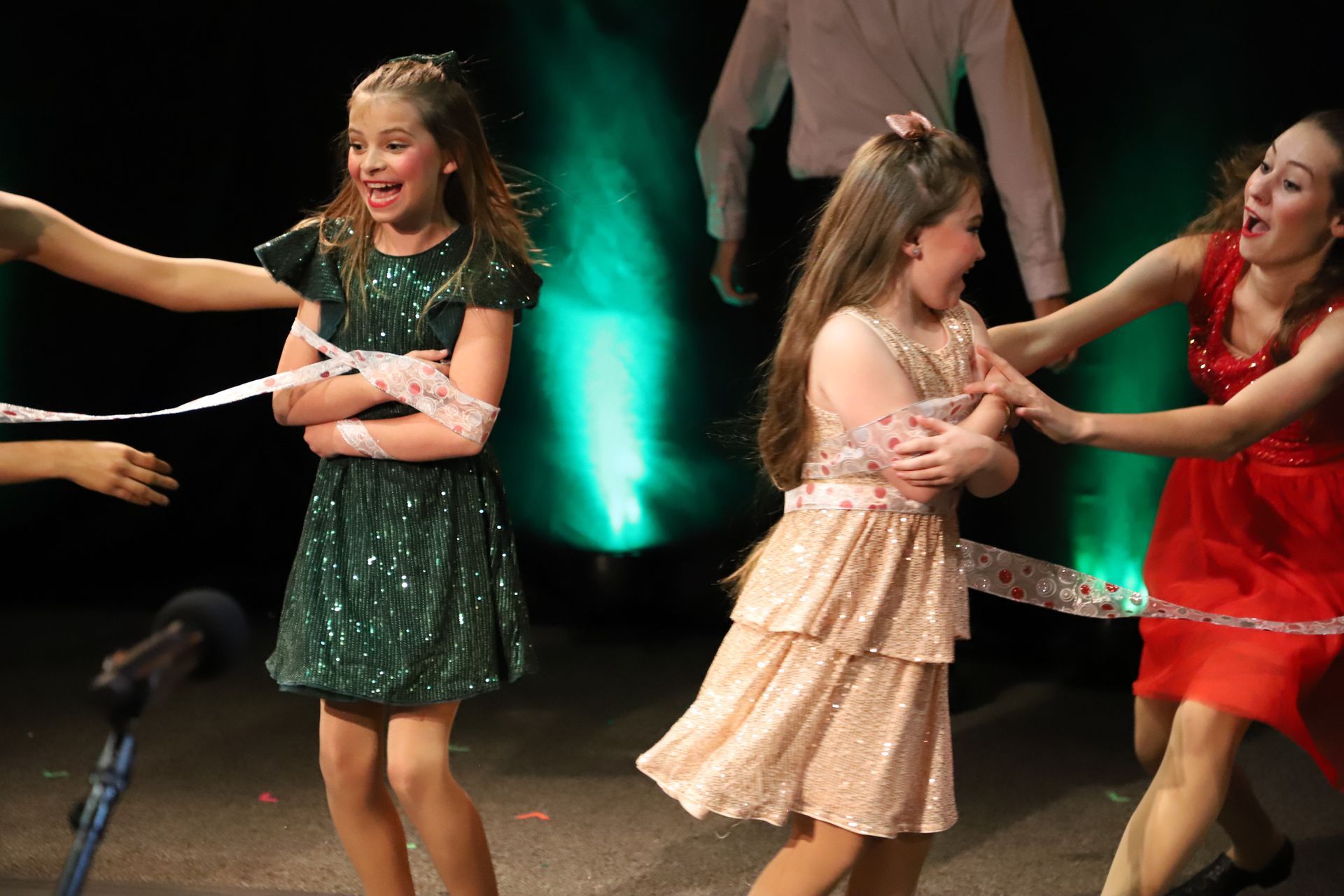 A group of young girls are playing with ribbons on a stage.